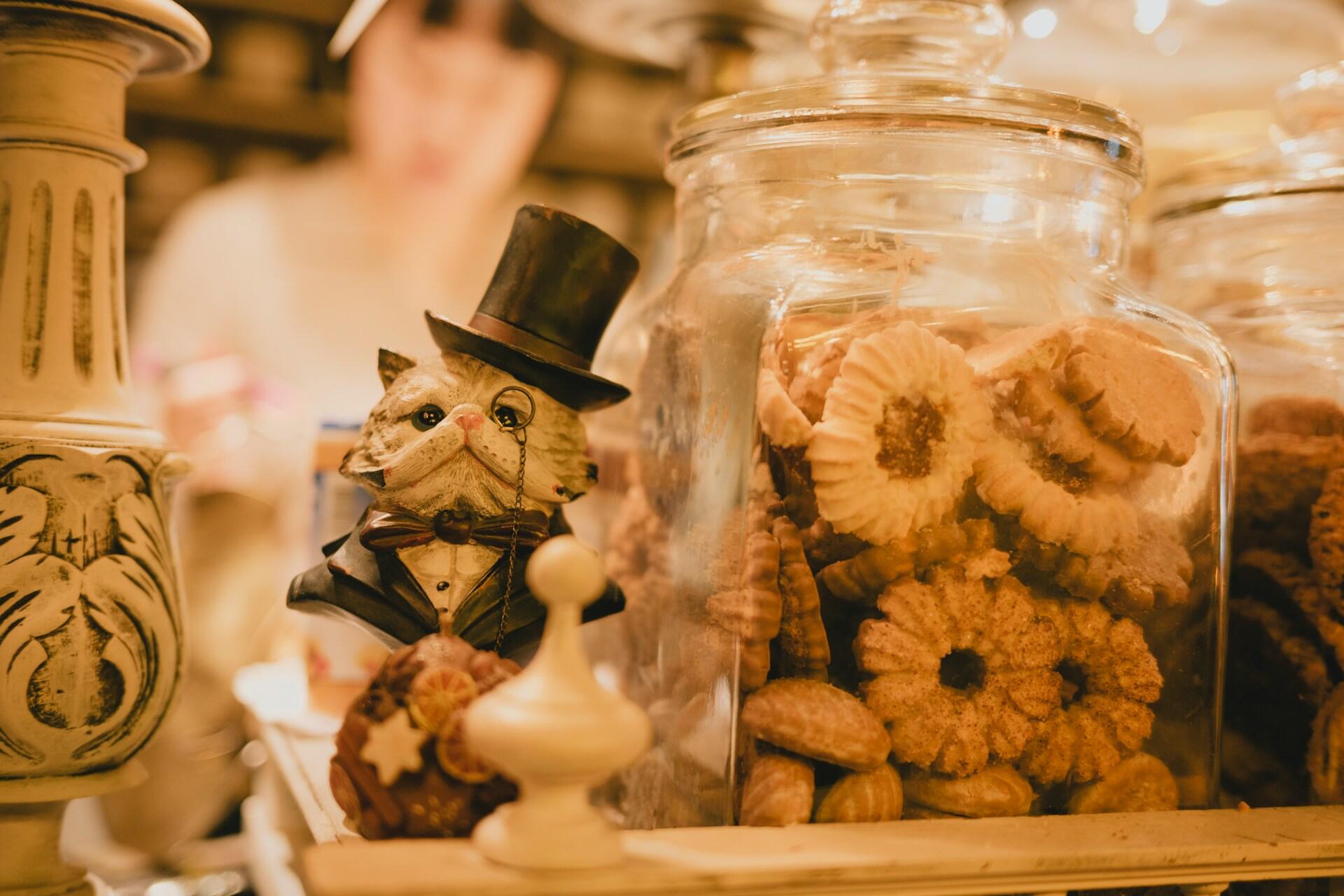 Decorative cat figure beside glass jars filled with biscuits