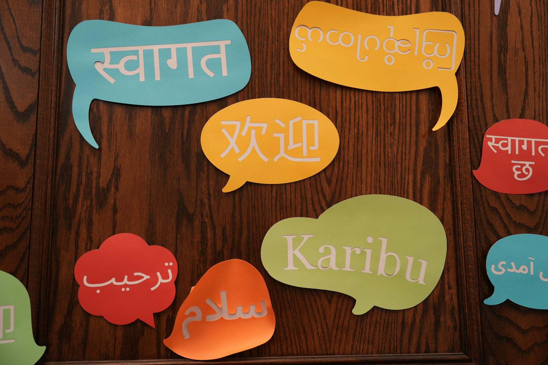 Colourful speech bubbles with words in different languages on a wooden wall