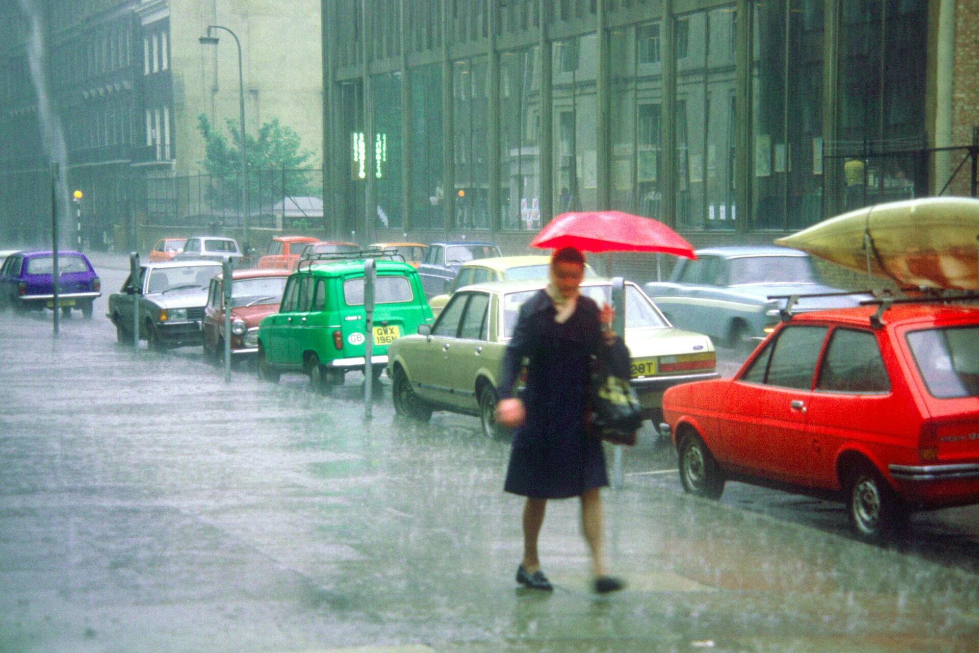 Person with a red umbrella walking through a flooded city street