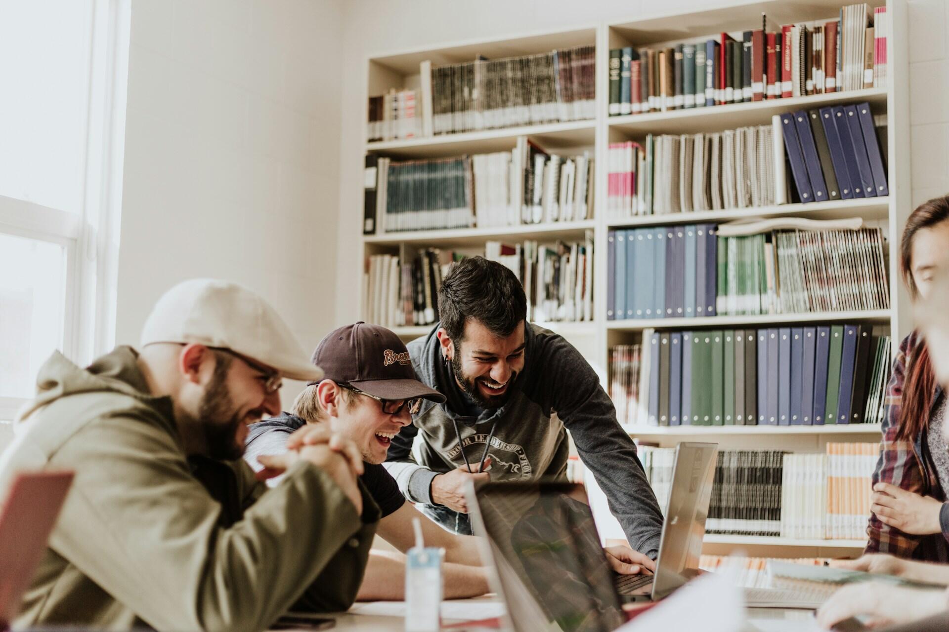 Students laughing together at a table in a library
