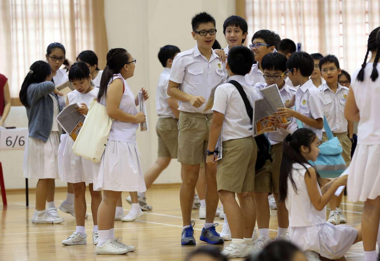 A group of schoolchildren in uniforms interacting in a school hall.