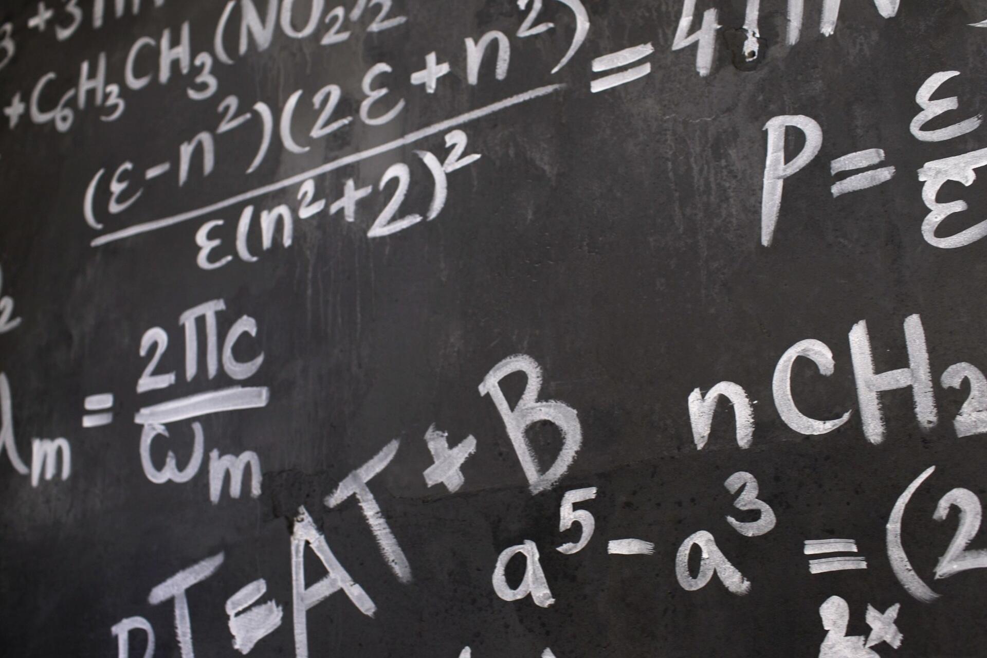 Advanced mathematical equations and formulas displayed on a classroom blackboard for H2 Mathematics revision.