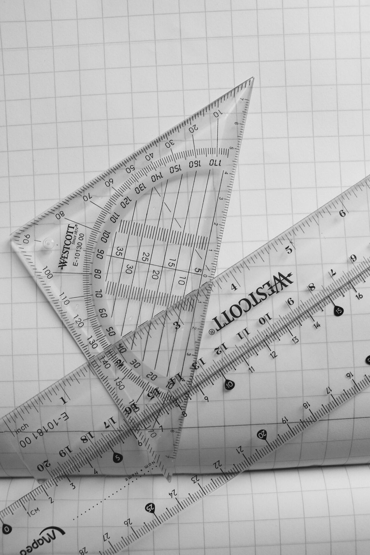 H2 Maths geometry tools including rulers and set squares placed on graph paper for mathematical drawing and measurement