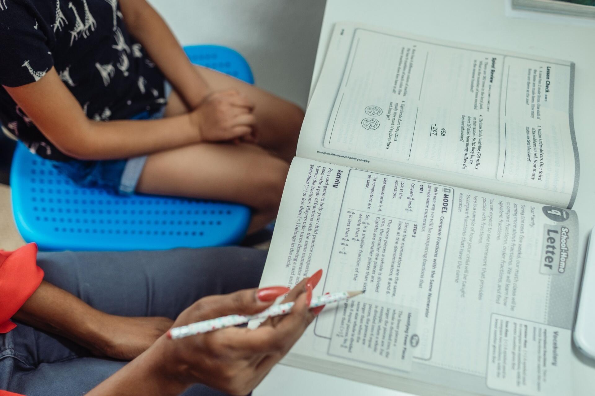 H2 Maths private tutor guiding a student through mathematics concepts using a workbook during a one-to-one tuition session