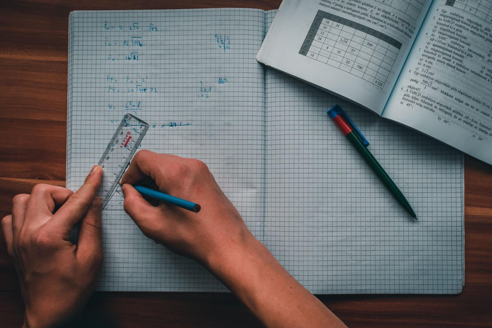 Student solving H2 Maths problems using a ruler and notebook during A-Level mathematics revision