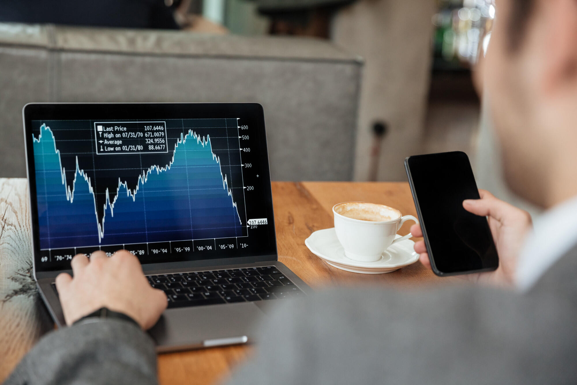Man focused on laptop displaying a stock market graph, analyzing financial data and trends.