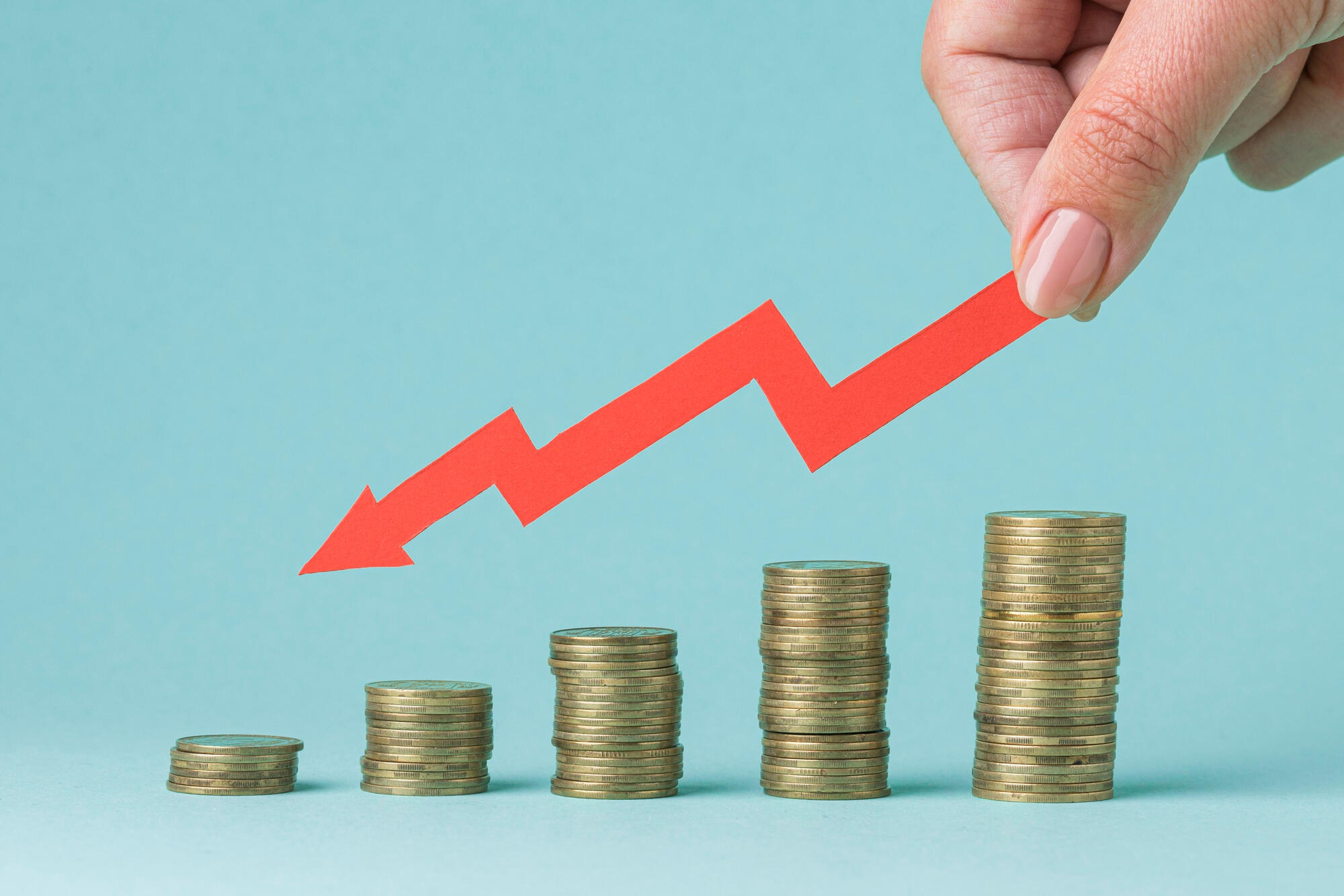 A hand points to a graph featuring a prominent red arrow indicating upward trends.