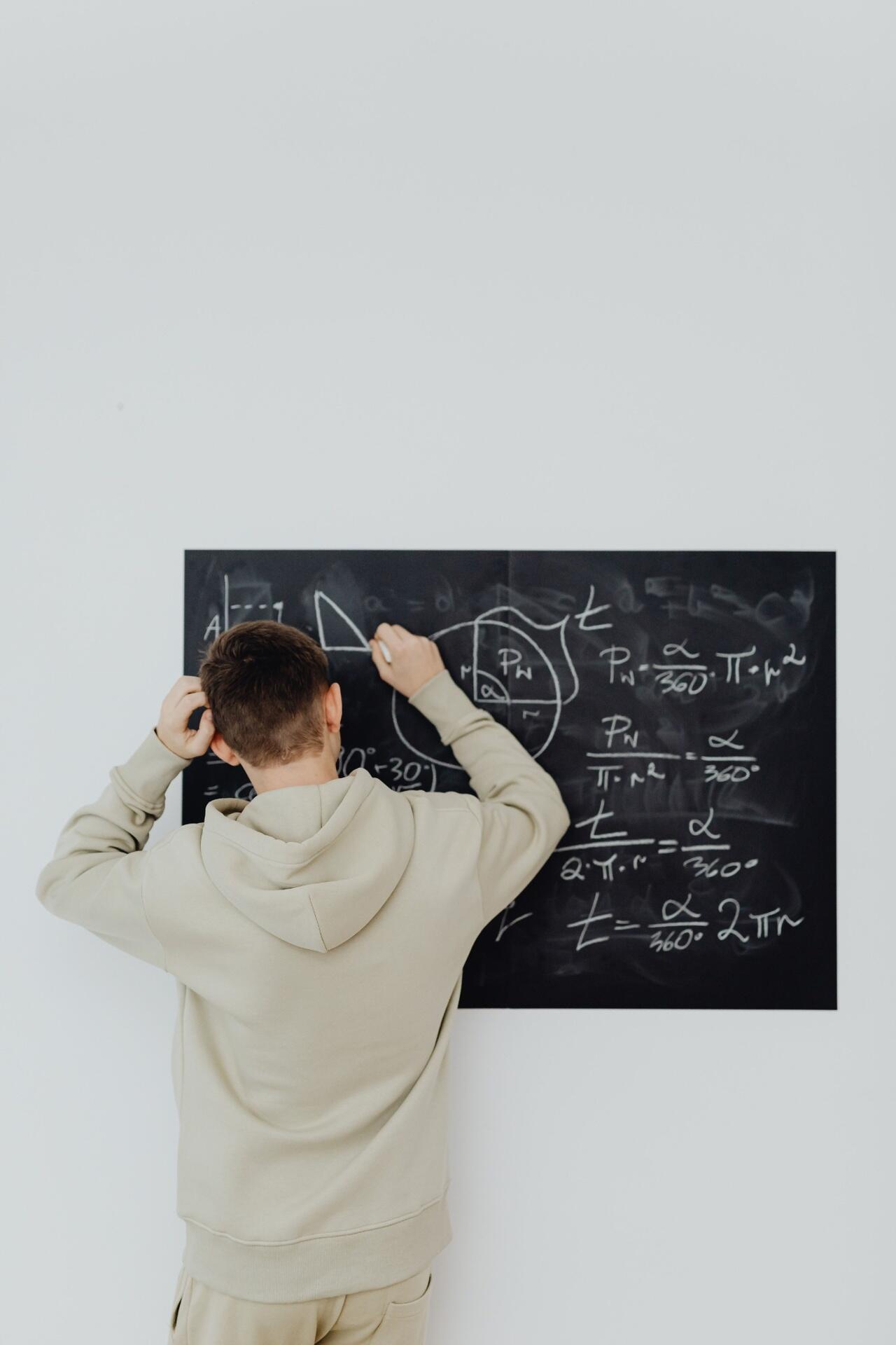 Student solving mathematical equations on a classroom board while studying H2 Mathematics concepts.
