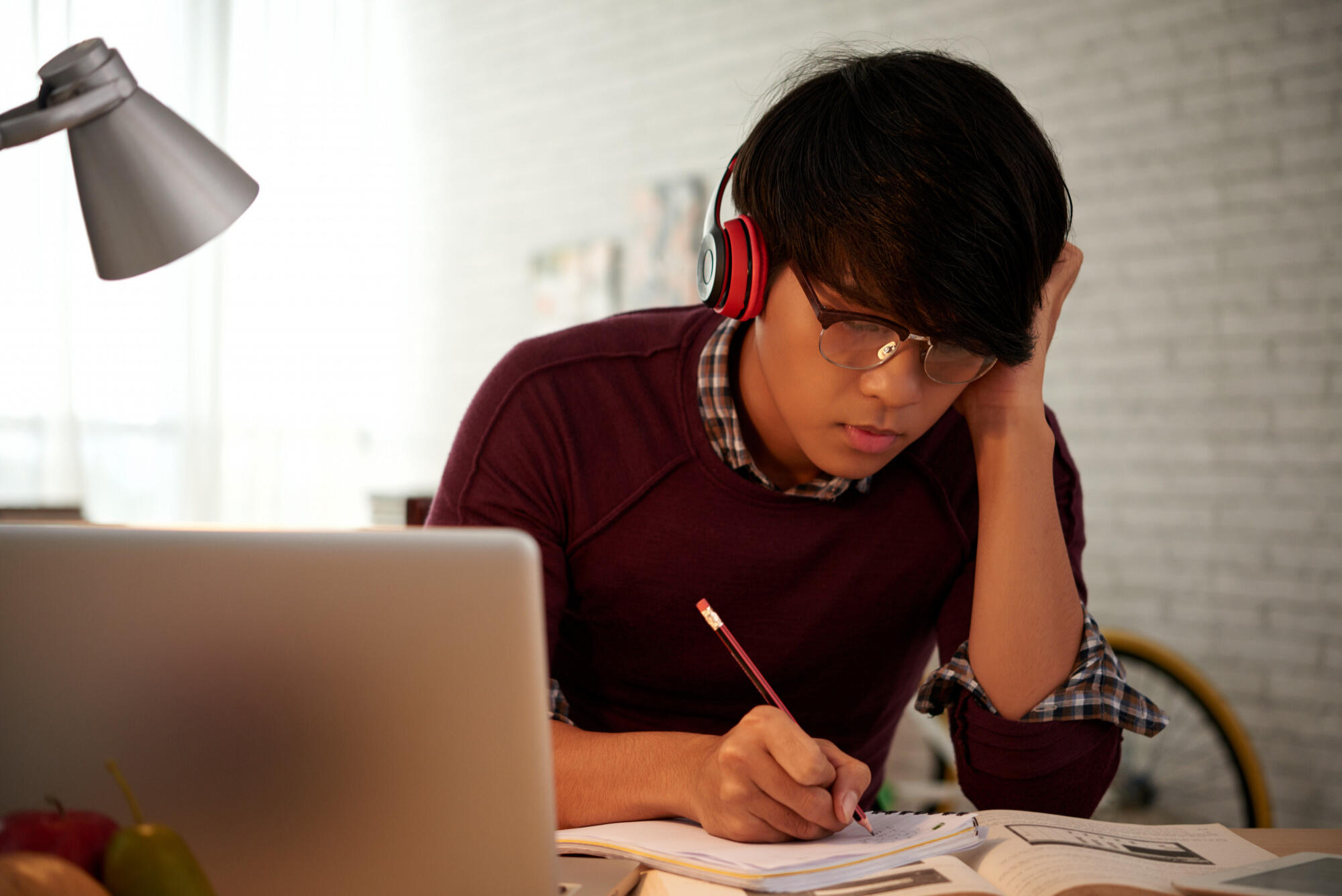 A man wearing headphones sits at a desk, focused on his work with a computer in front of him.