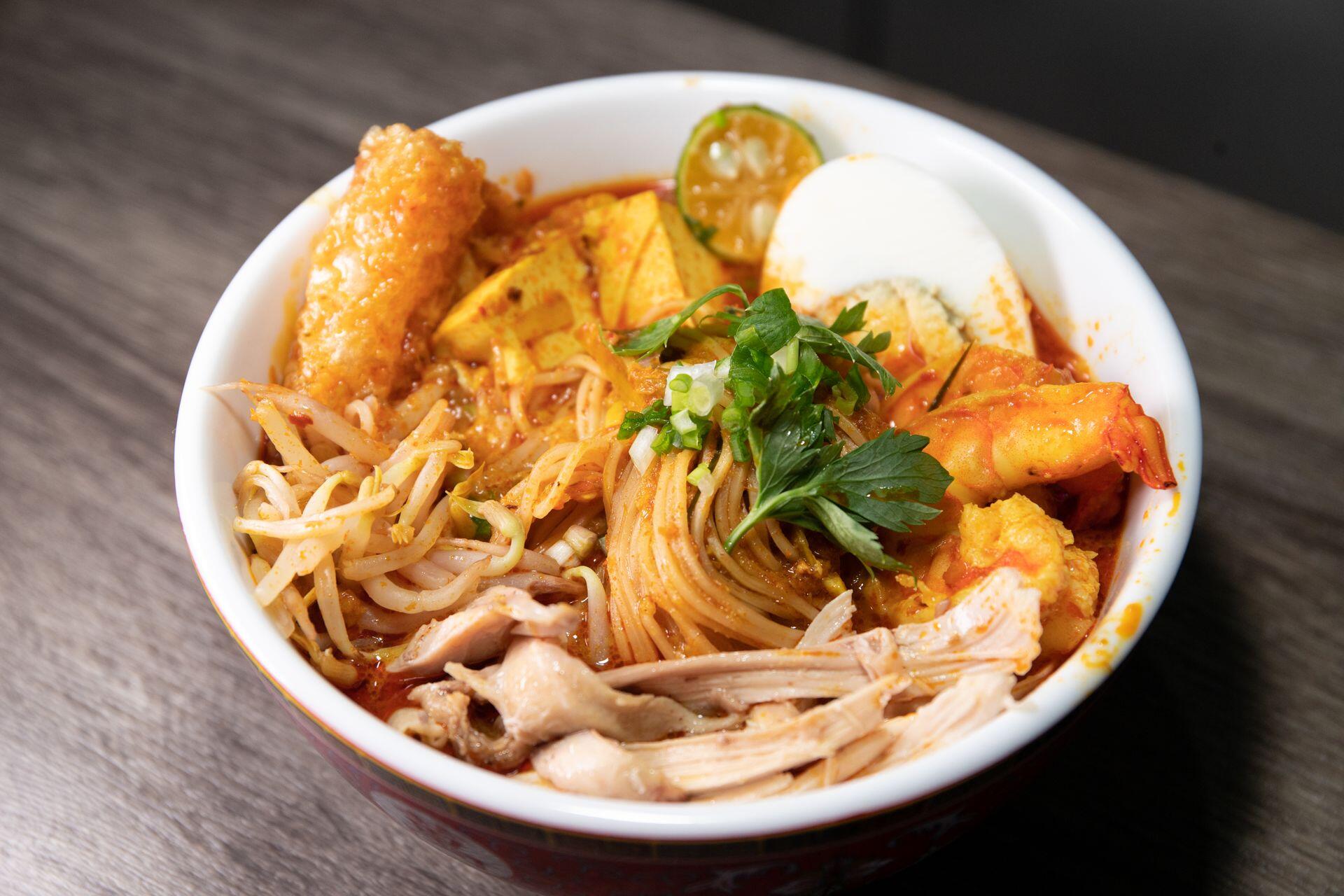 Close-up of a flavorful Asian noodle soup in a bowl, showcasing fresh ingredients like chicken, shrimp, and eggs