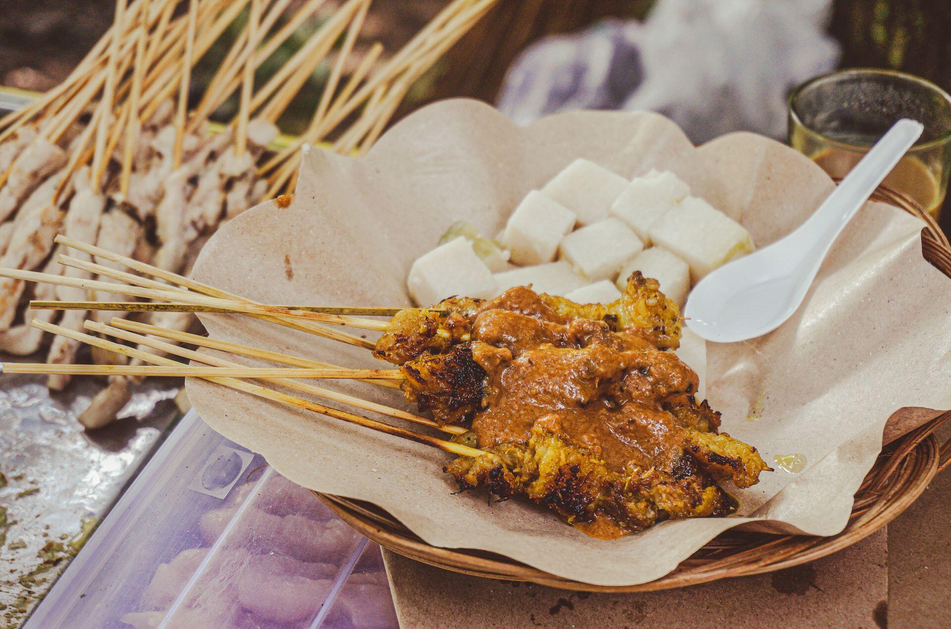 Tantalizing satay skewers with rich peanut sauce served with rice cakes, highlighting traditional street food.
