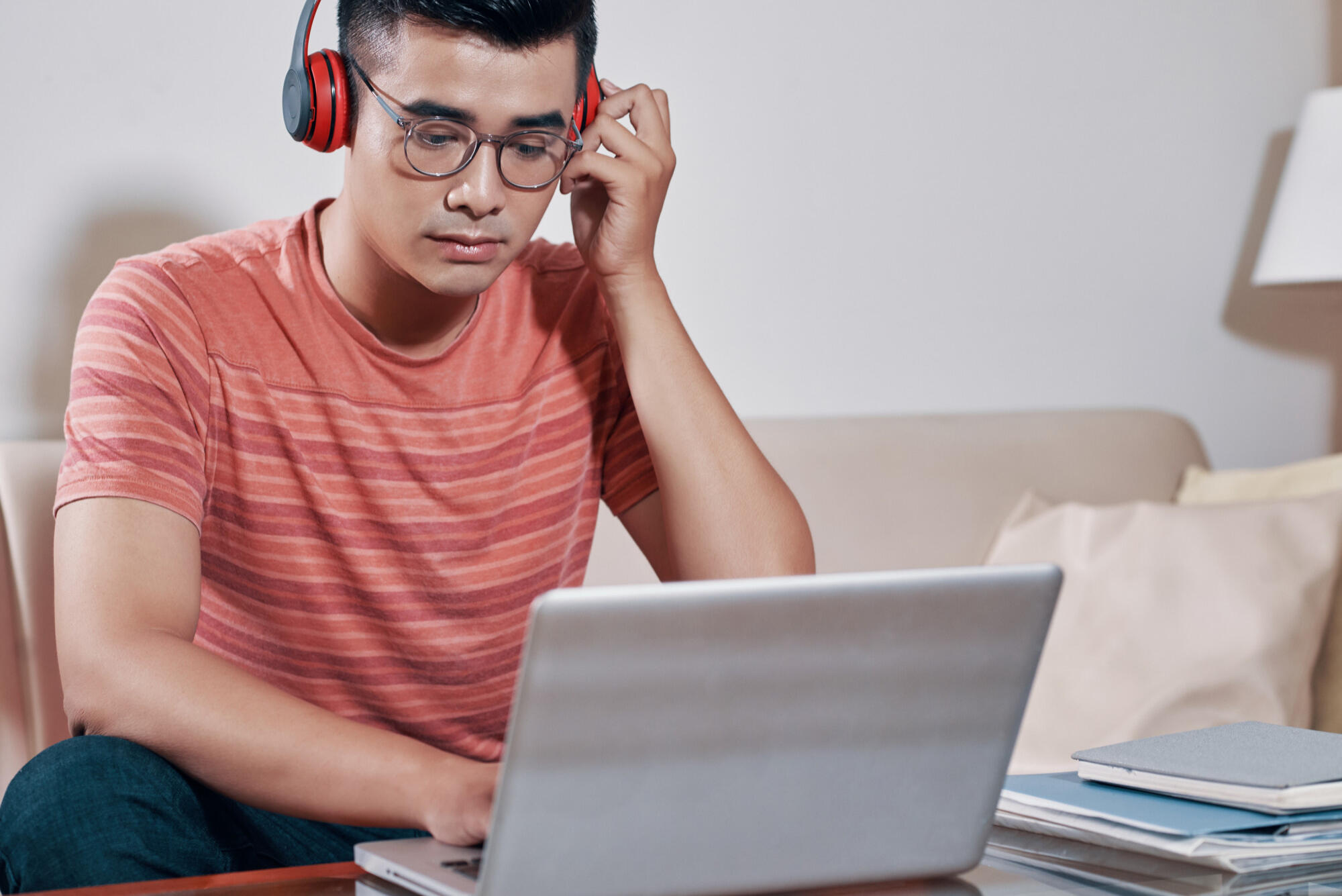 A man wearing headphones sits on a couch, focused on his laptop, creating a relaxed and engaged atmosphere.