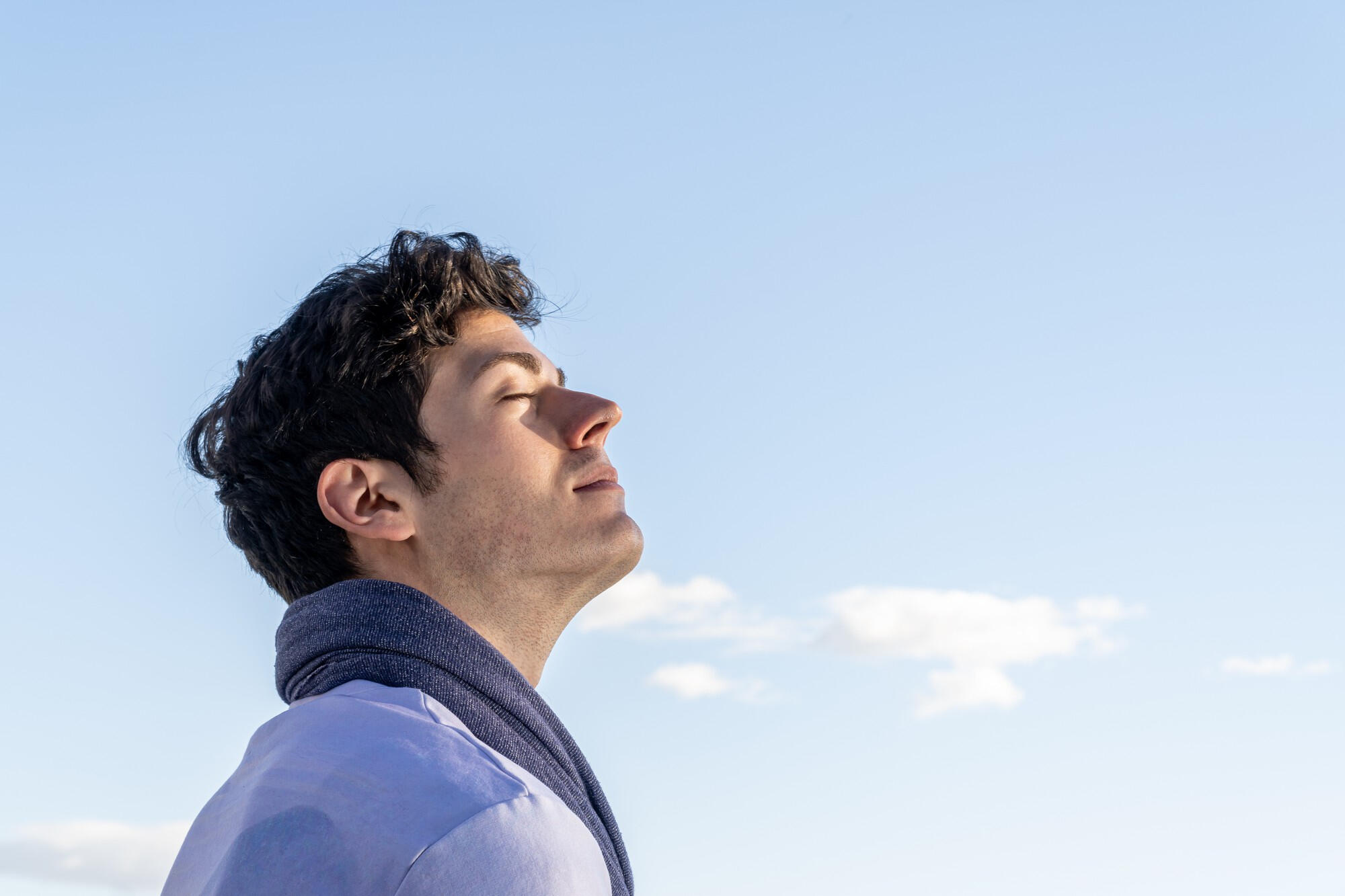 A man tilts his head back, staring at the sky, reflecting a moment of curiosity or wonder.