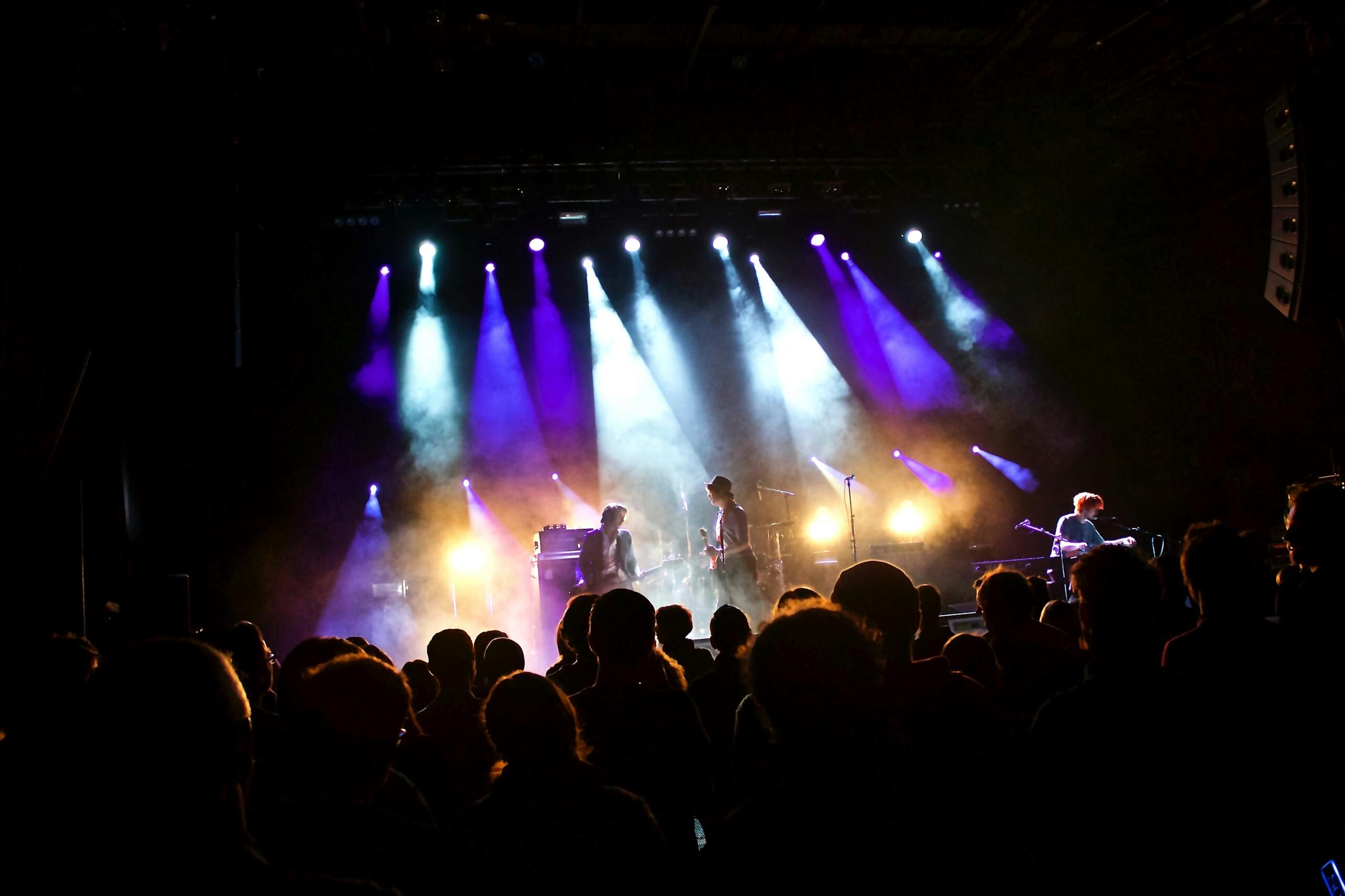 A lively band entertains the audience on stage, with striking lights creating an engaging visual experience.