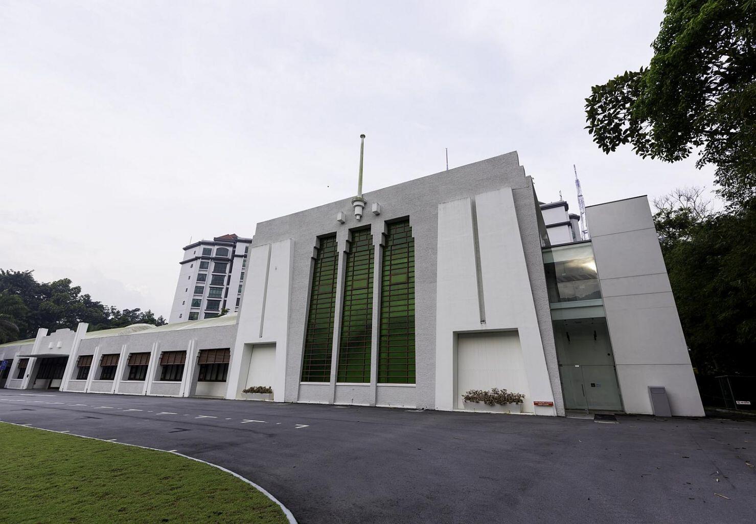 Exterior view of the Former Ford Factory building with its distinctive Art Deco facade, green-tinted windows, and a central flagpole.