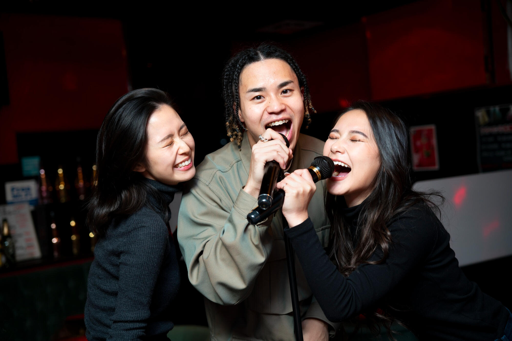 Three friends singing into a microphone at a bar, creating a joyful and entertaining environment for patrons.