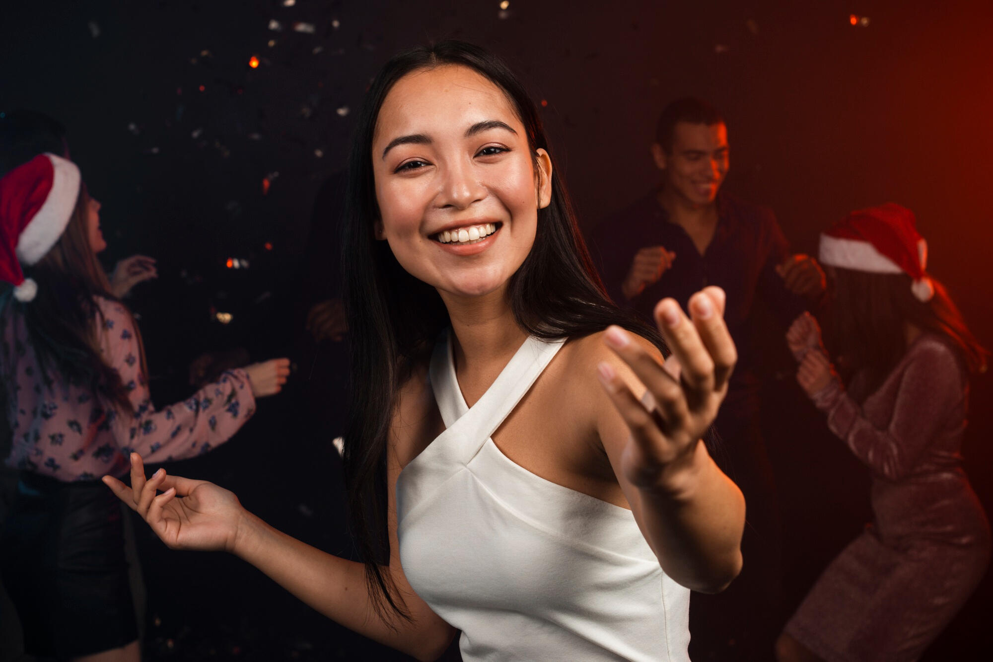 A woman in a white dress dances joyfully in front of an audience, showcasing her graceful movements.