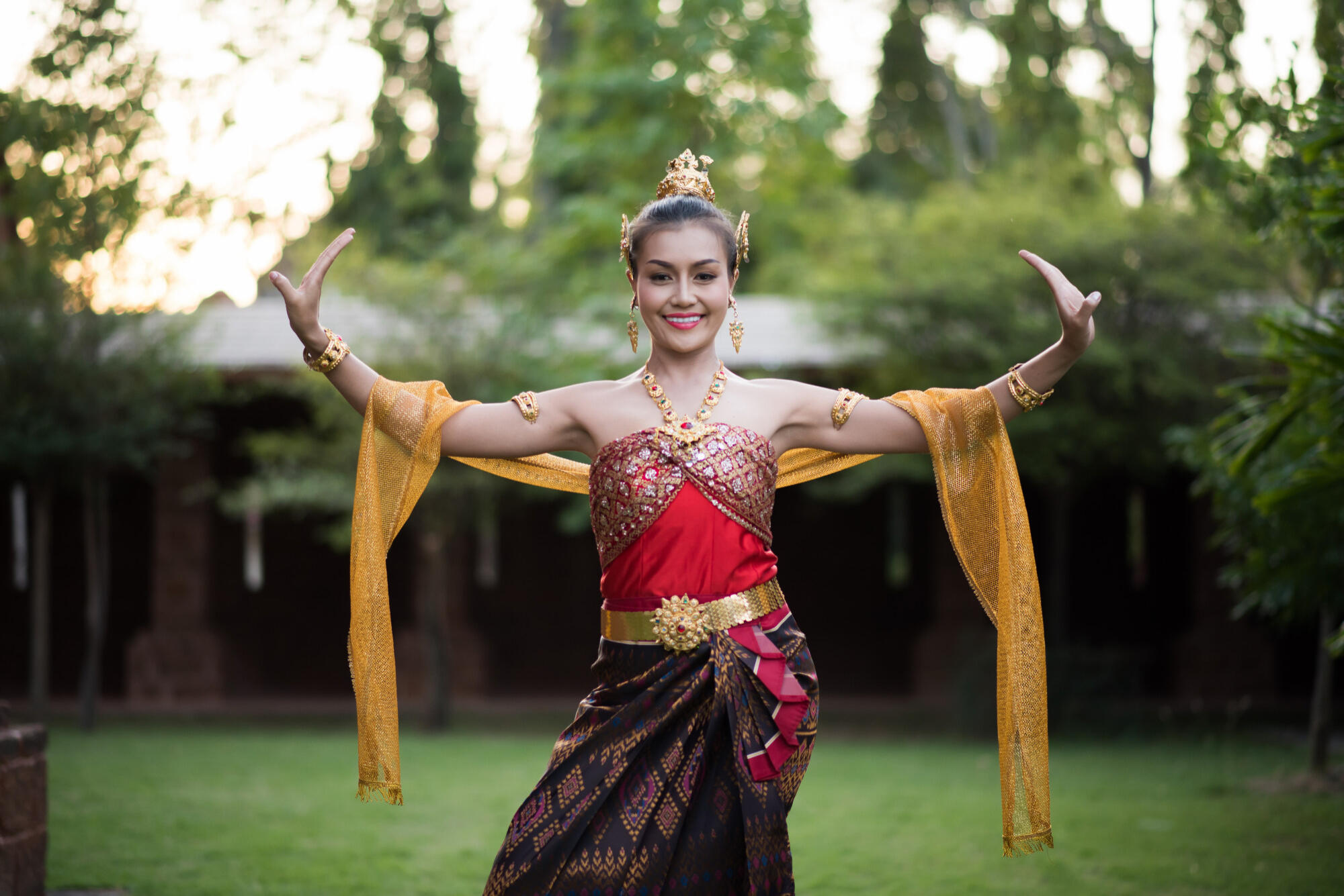 A woman performs a traditional Thai dance, adorned in a colorful costume with intricate patterns and accessories.