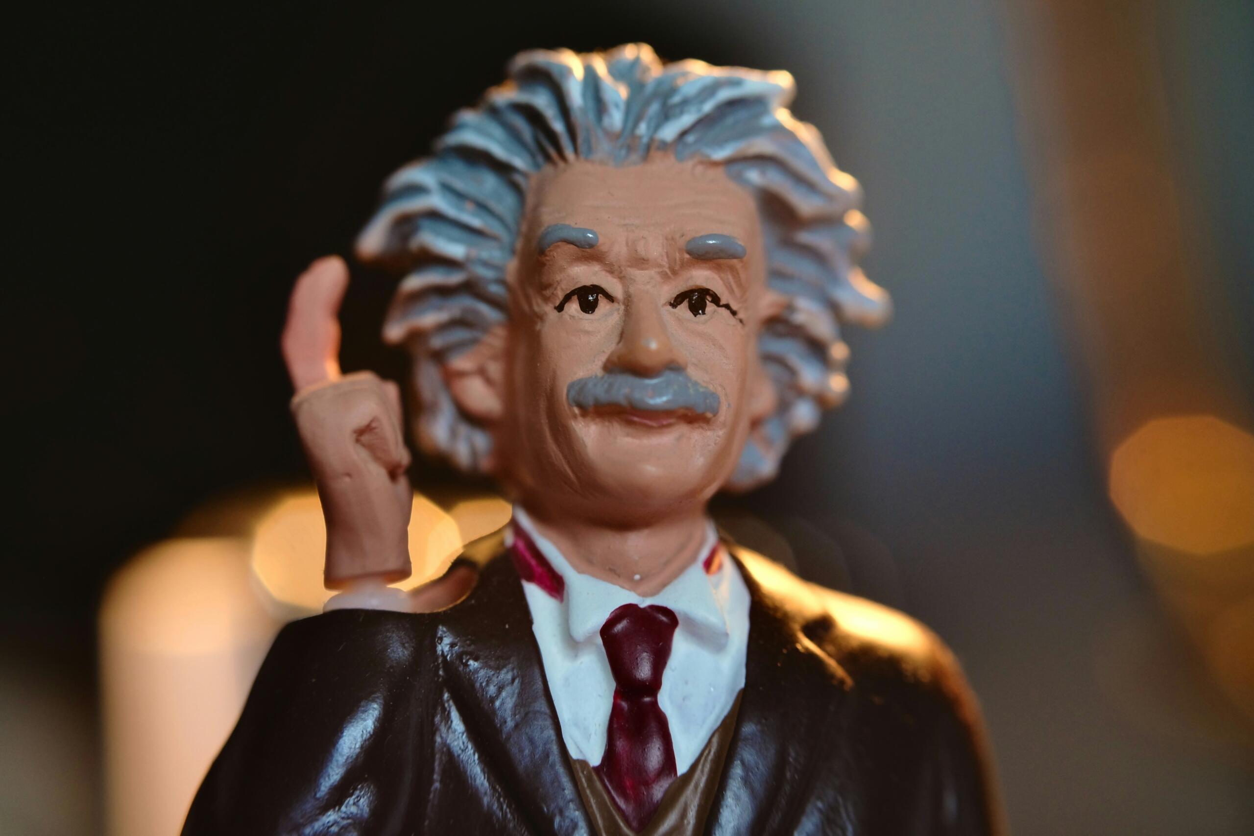 Albert Einstein lutka, ki ima dvignjano desno roko in kaže prst.