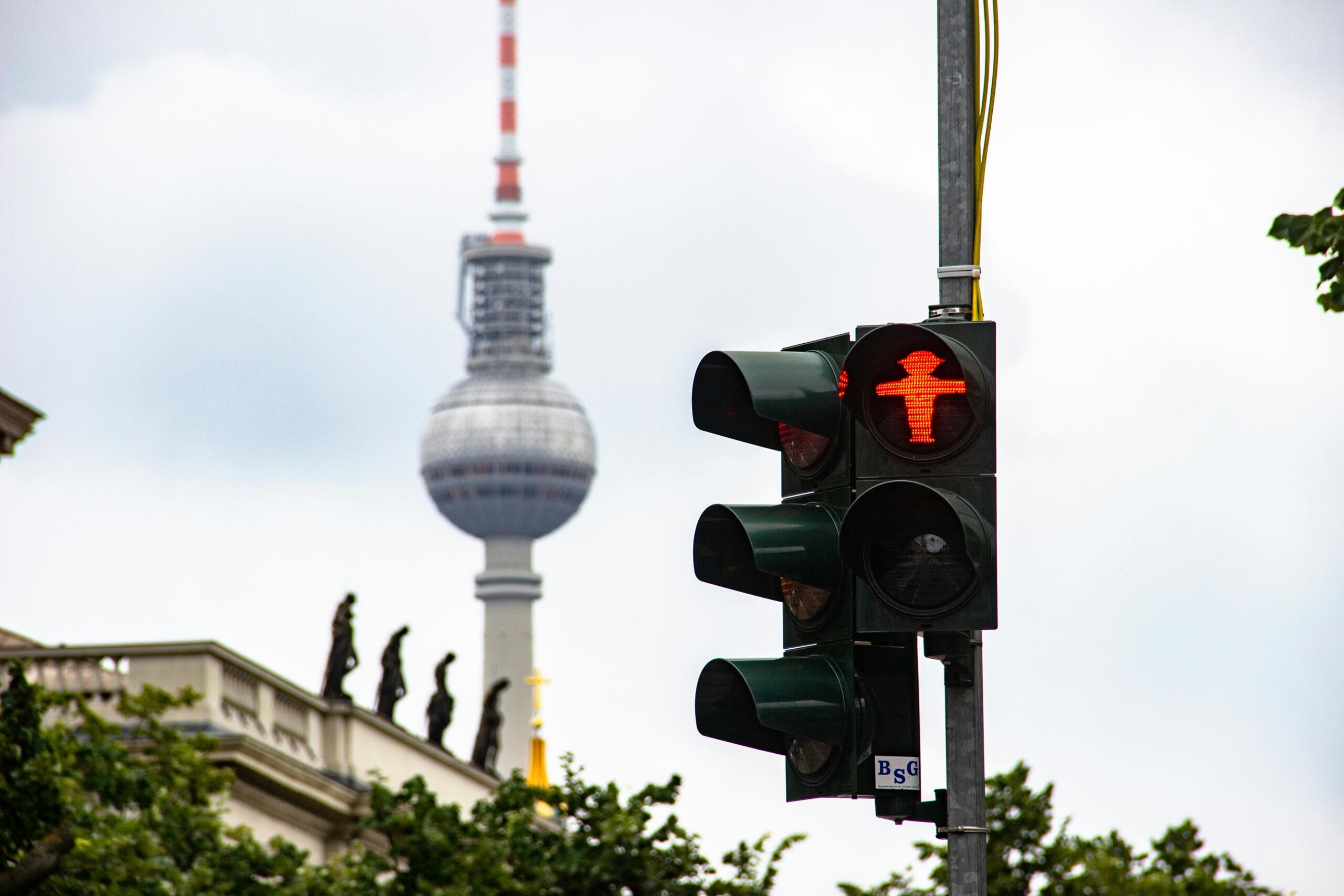 semafor z rdečim Ampelmann znakom in berlinskim stolpom v ozadju