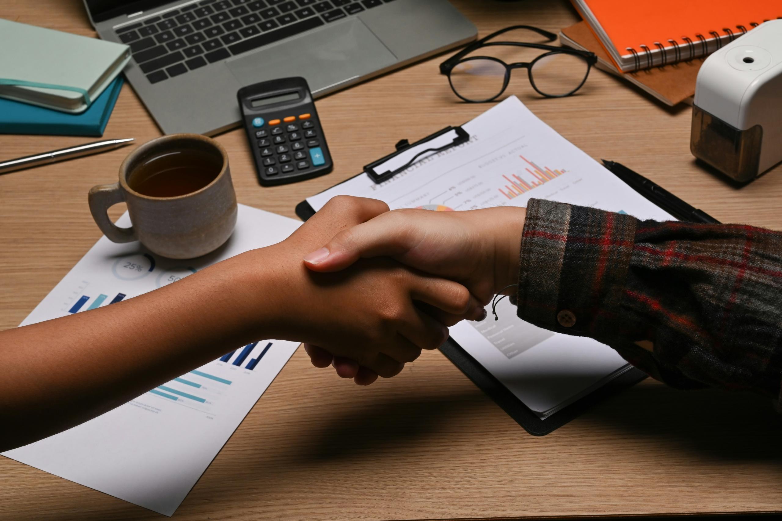 people shaking hands over a desk space