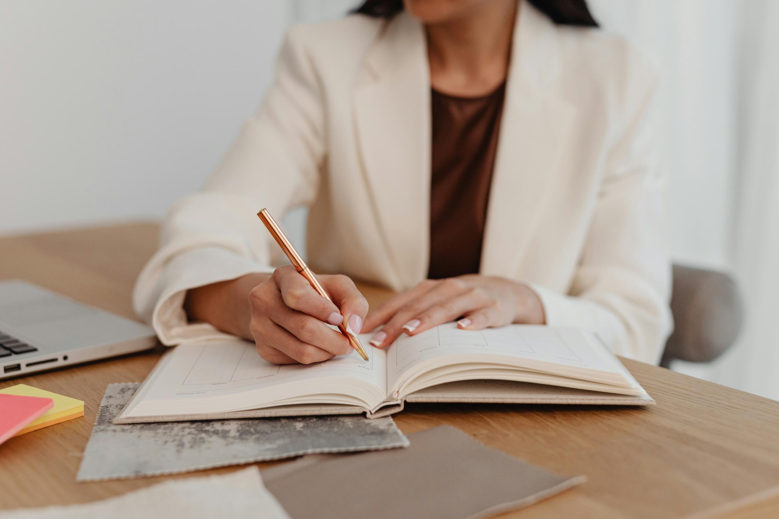 woman writing in a notebook on a desk