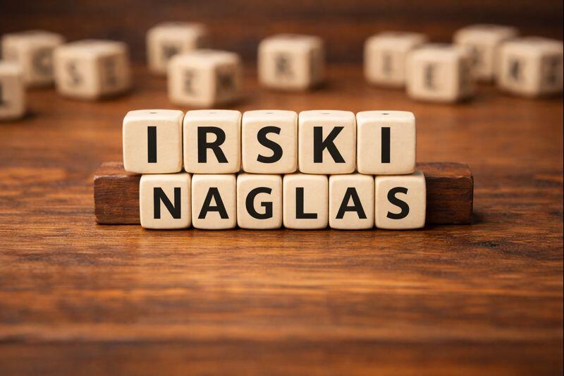 Lesene črkovne kocke na mizi, ki sestavljajo napis »IRSKI NAGLAS«.