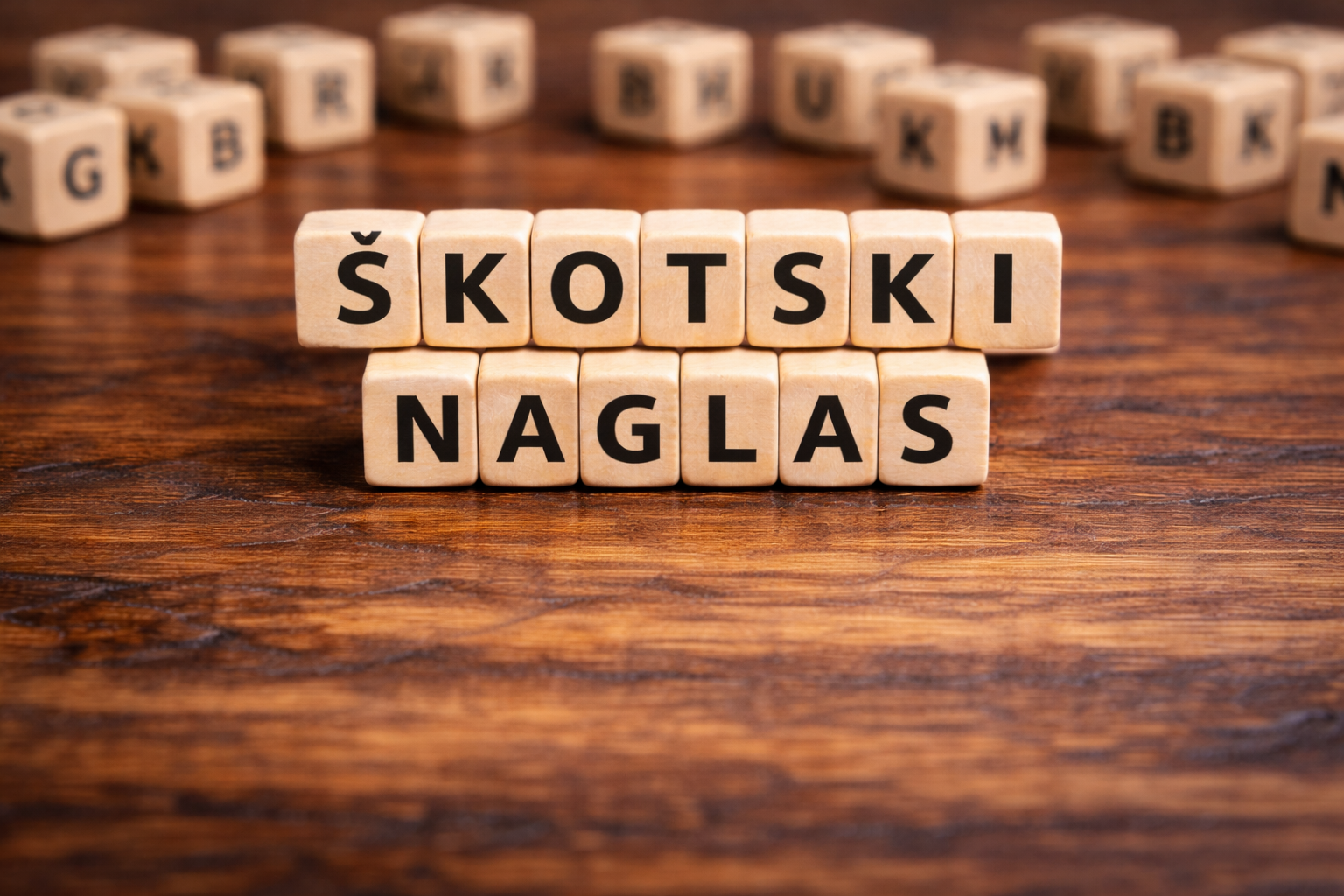Lesene črkovne kocke na mizi, ki sestavljajo napis »ŠKOTSKI NAGLAS«.