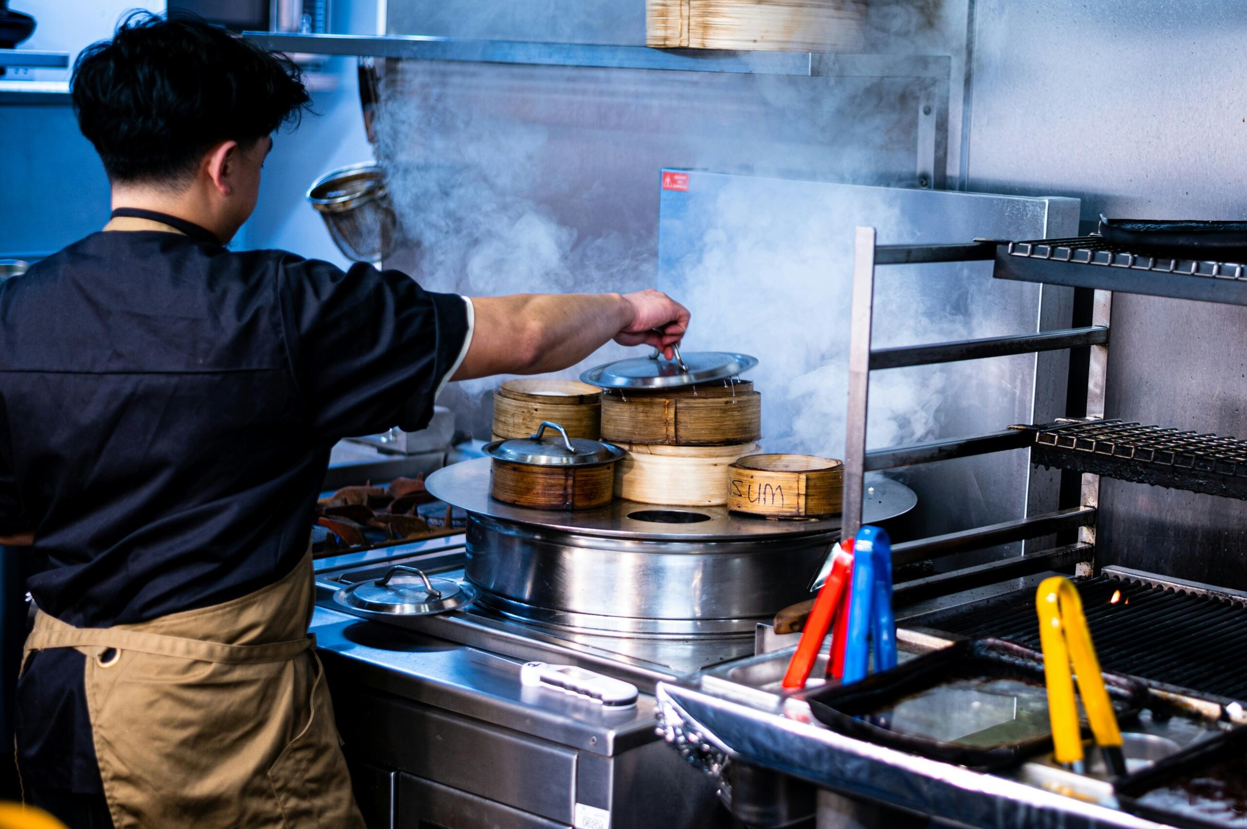 Kuhar pripravlja jedi s soparjenjem v profesionalni kuhinji