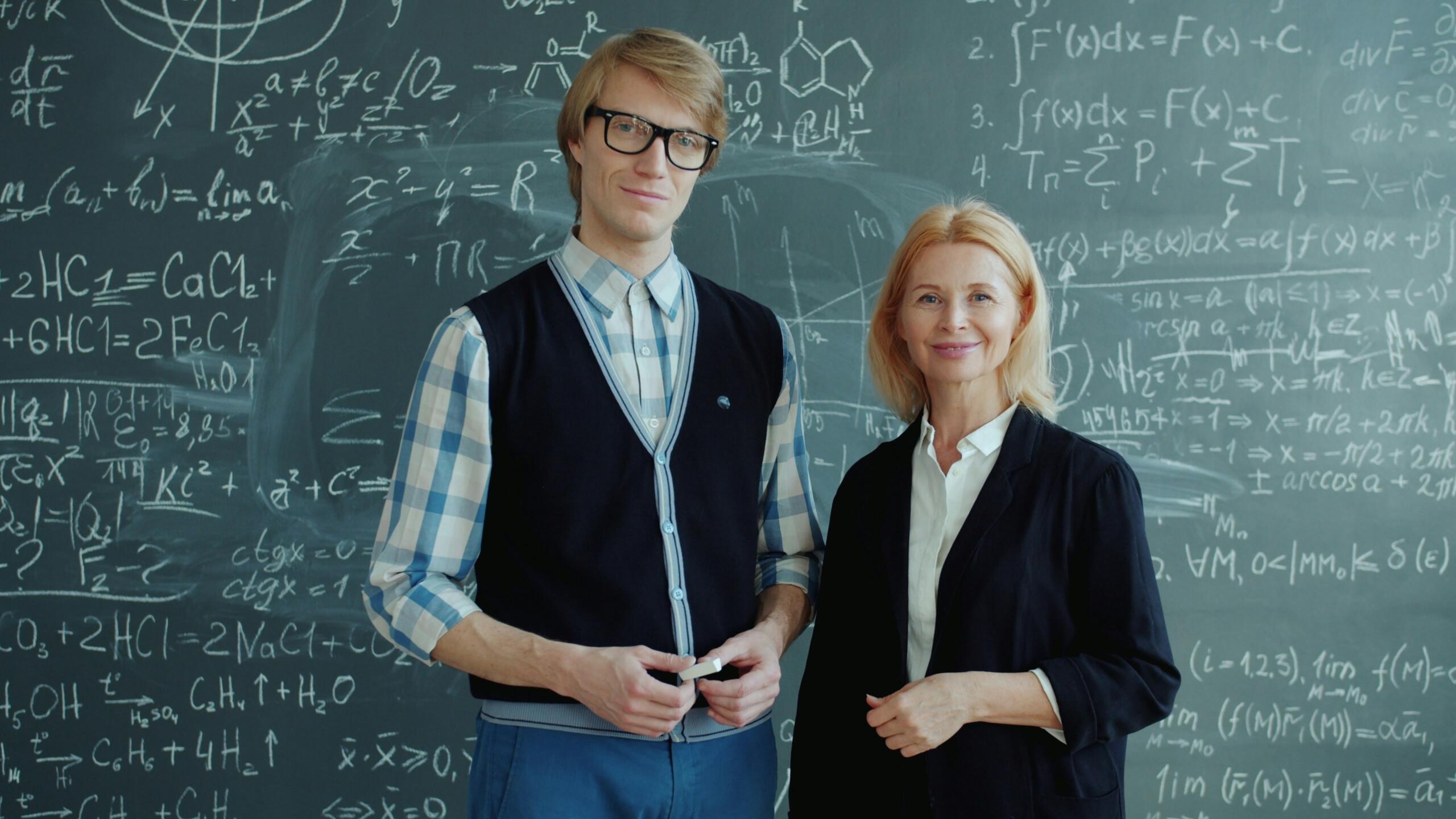 Dva profesorja matematike stojita pred tablo z enačbami in formulami.