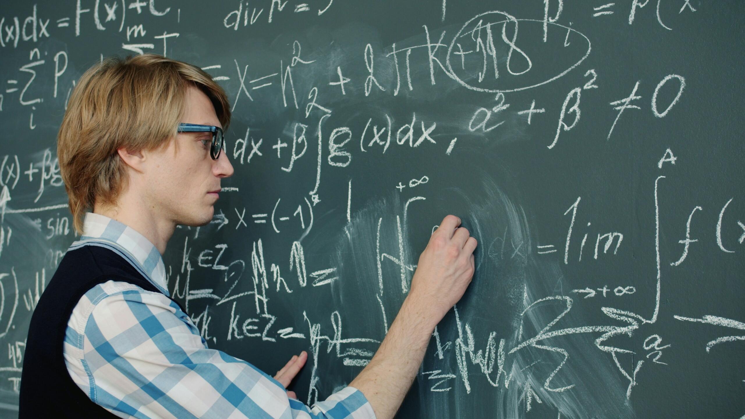 Študent piše matematične enačbe na tablo med ponavljanjem snovi.