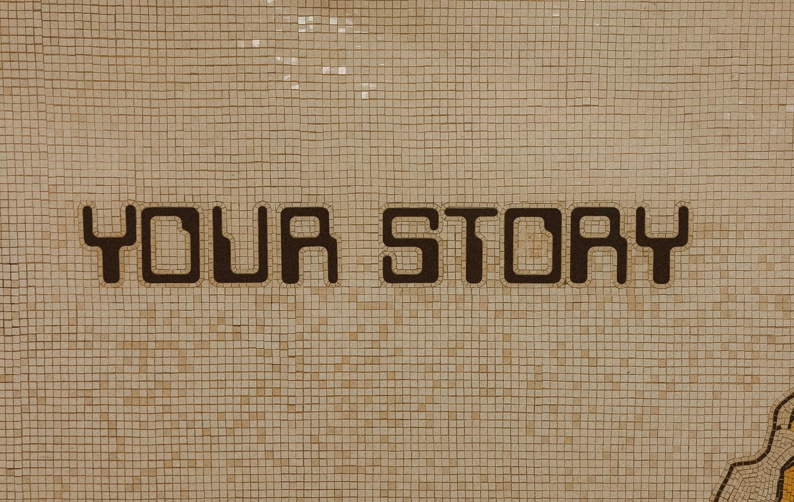 Napis »Your Story« na mozaični steni kot simbol osebne pripovedi in identitete.