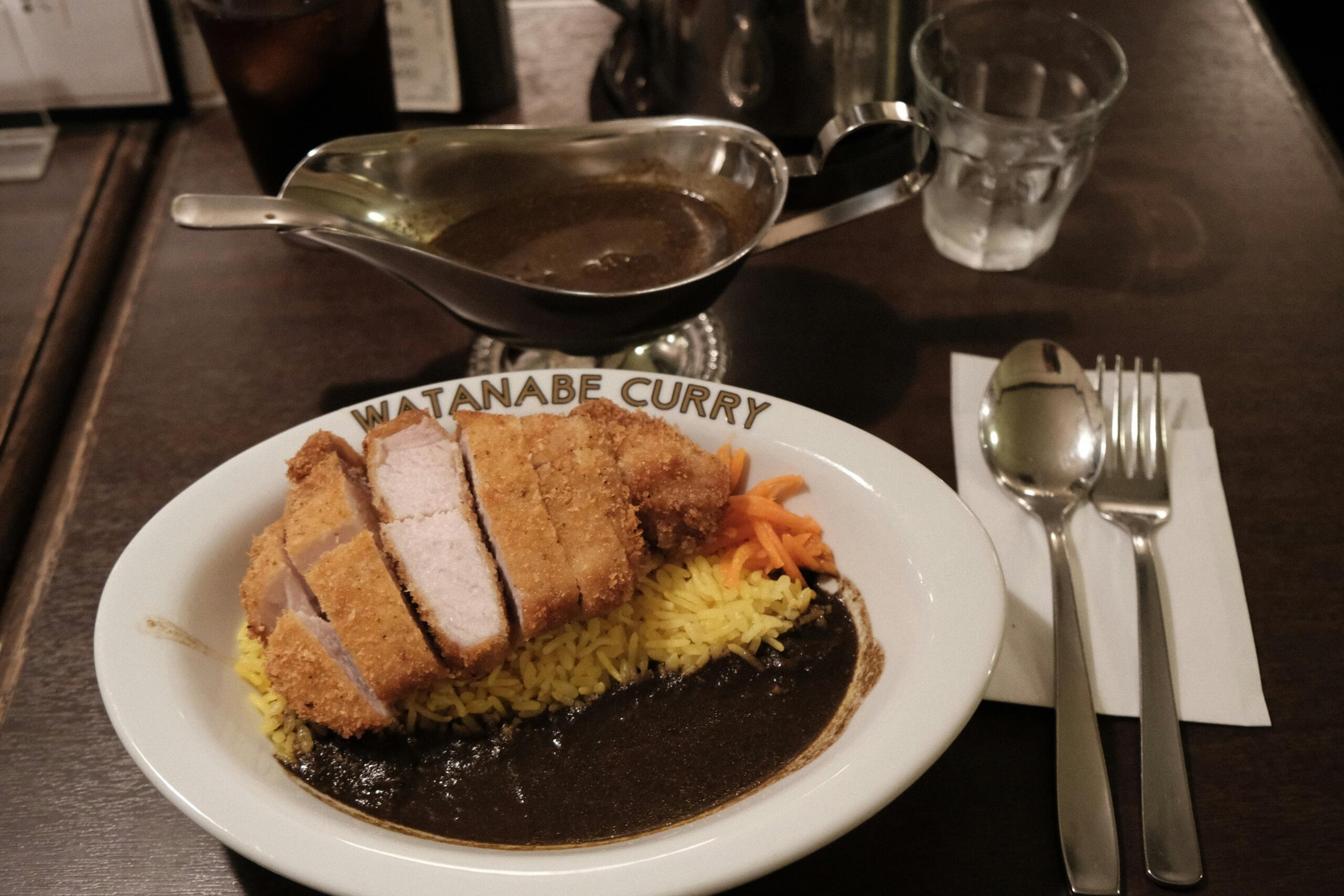 Krožnik katsu curry z rezinami hrustljavega tonkatsuja, rumenim rižem, temno curry omako in naribanim korenčkom