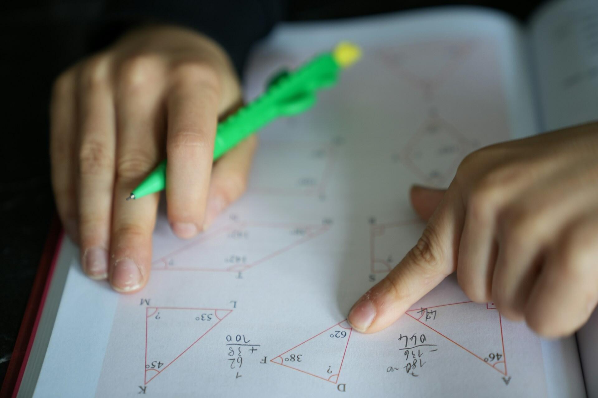 Ruky žiaka ukazujúce na geometrické úlohy v teste s trojuholníkmi a uhlami.