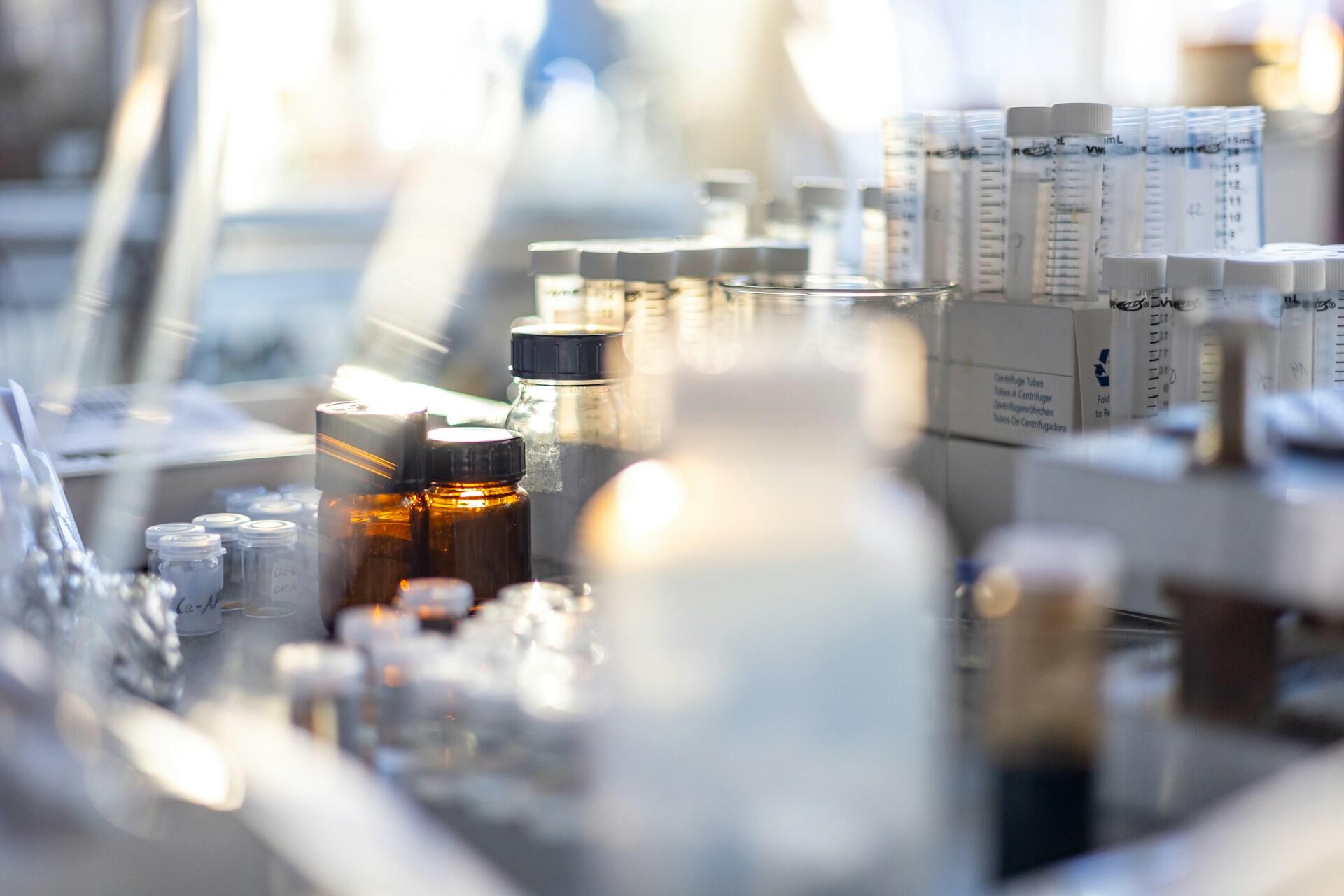 Sklenené a plastové fľaštičky, hnedé laboratórne nádoby a centrifugačné skúmavky na stole v laboratóriu
