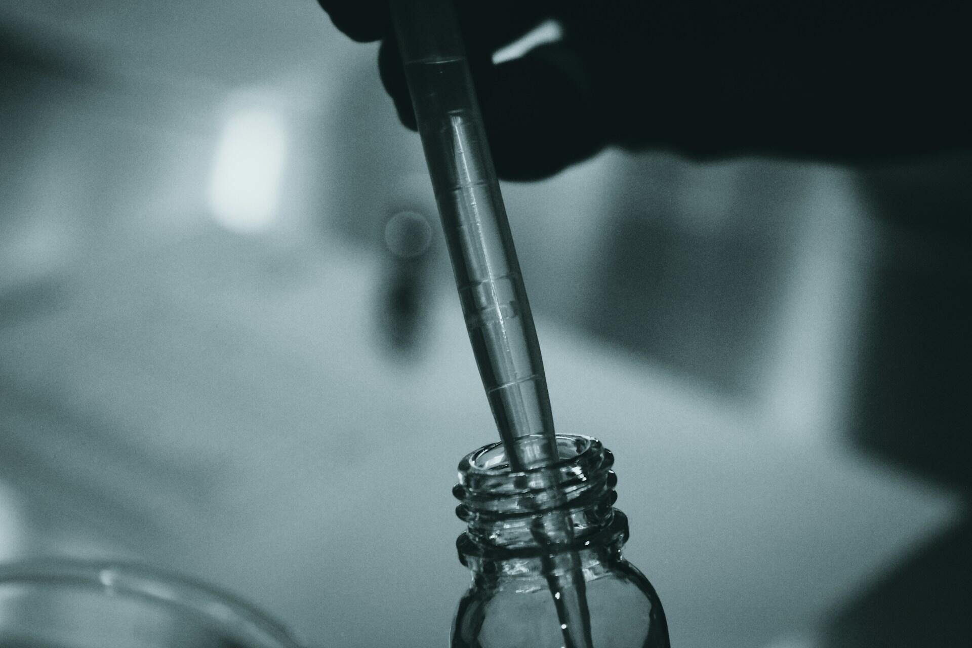 Pipeta ponorená vo fľaške počas chemického experimentu