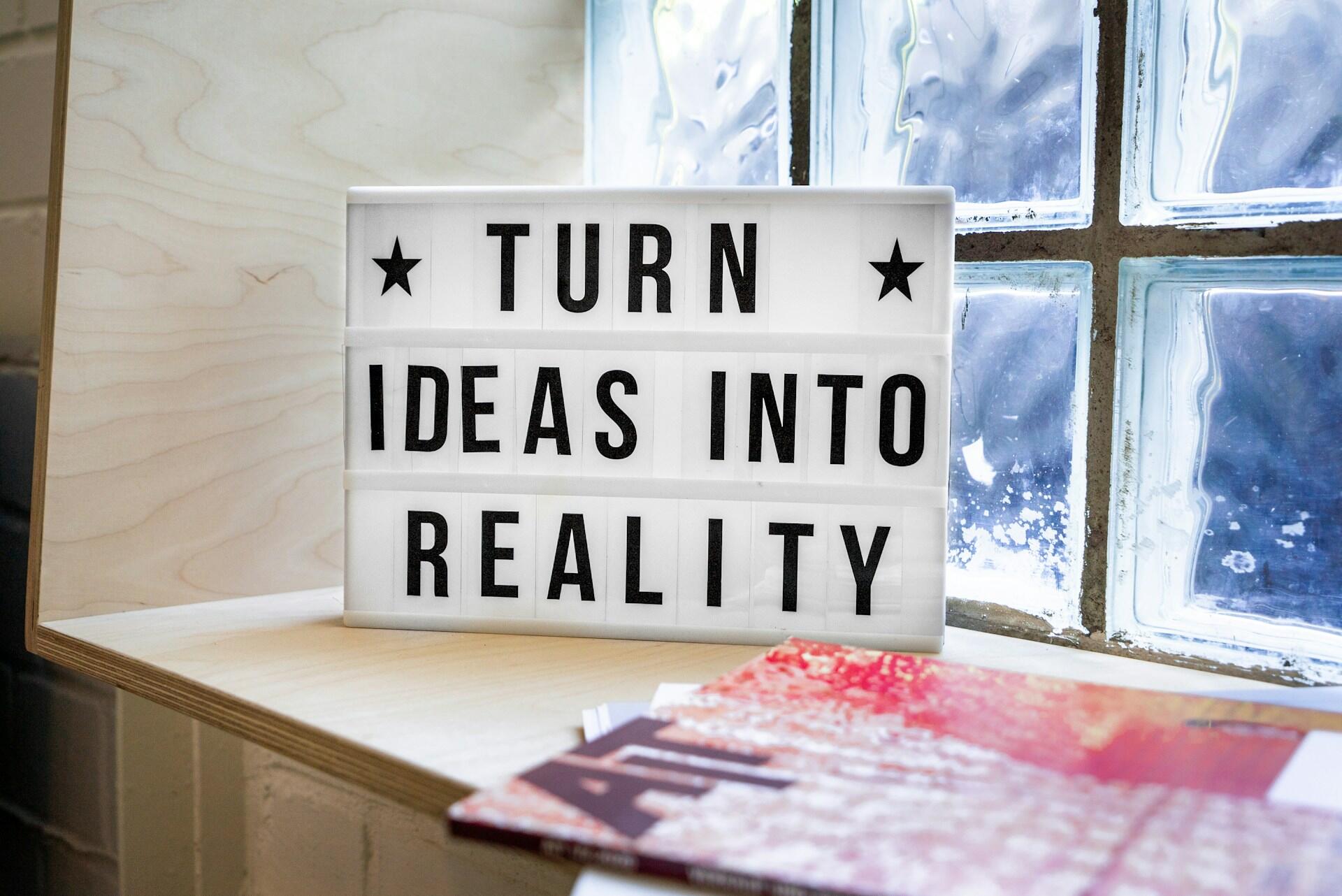 Motivačný nápis „Turn ideas into reality“ na svetelnej tabuli