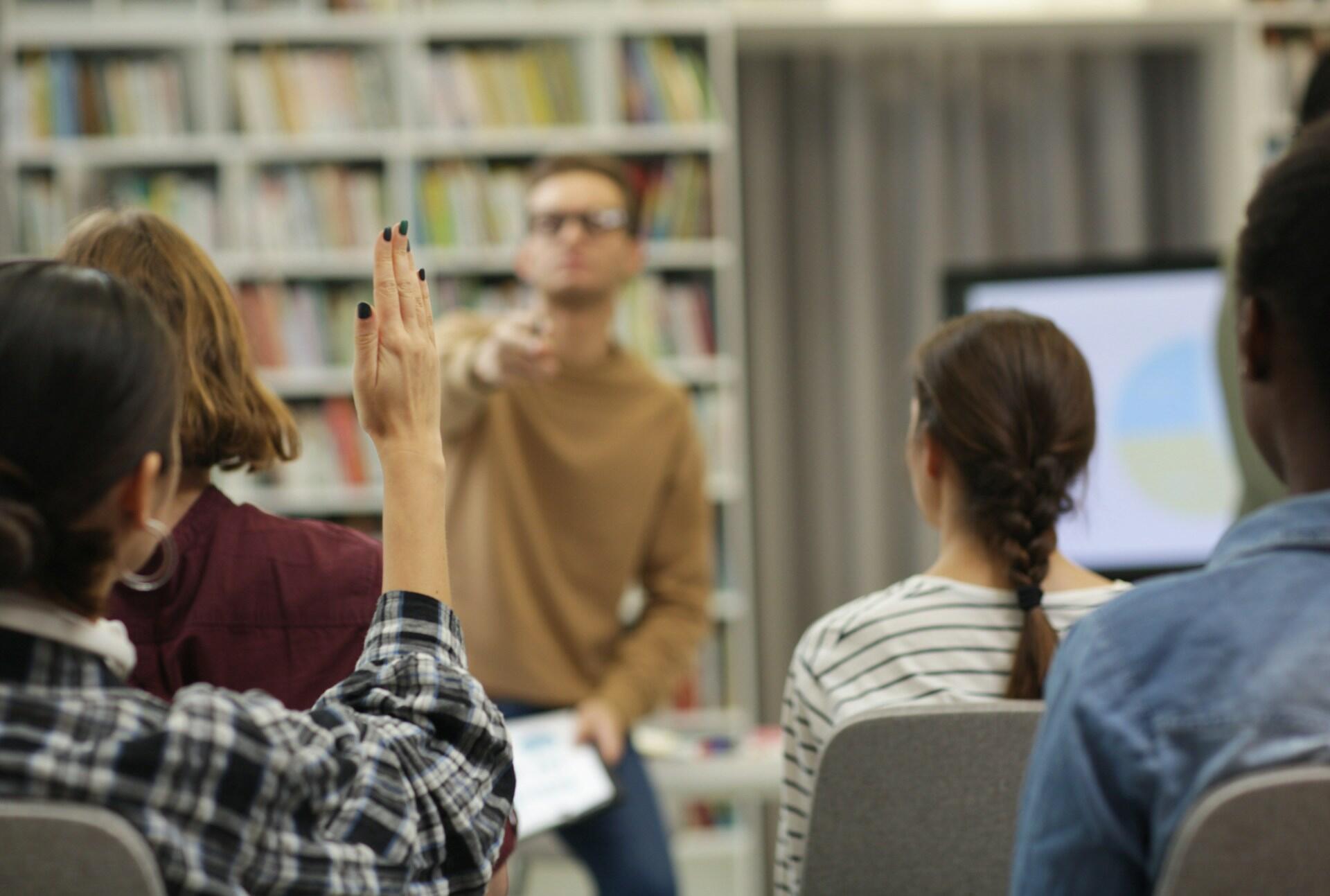 Študent sa hlási počas hodiny v učebni.