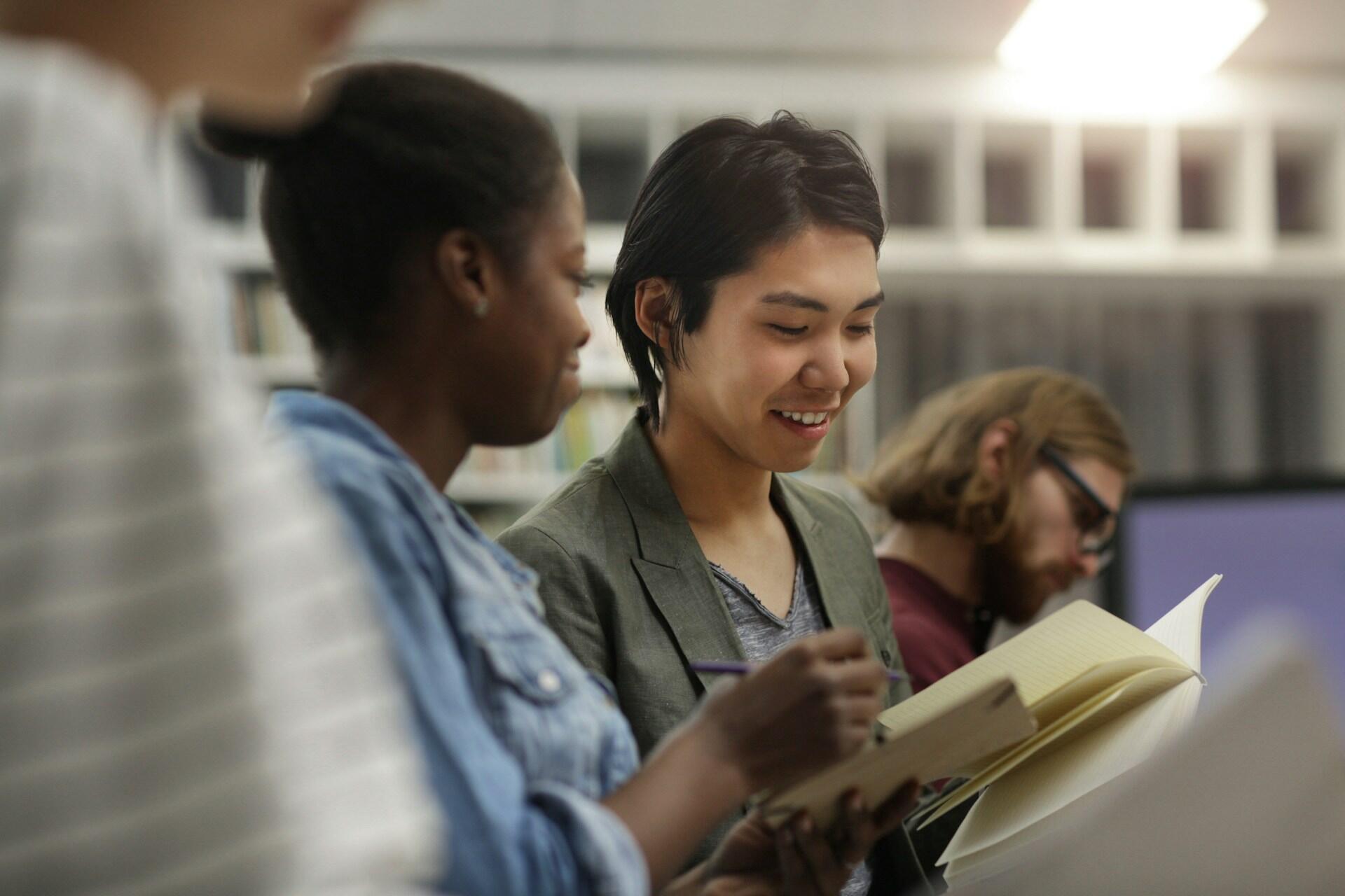 Skupina študentov si vymieňa poznámky a diskutuje pri učení.