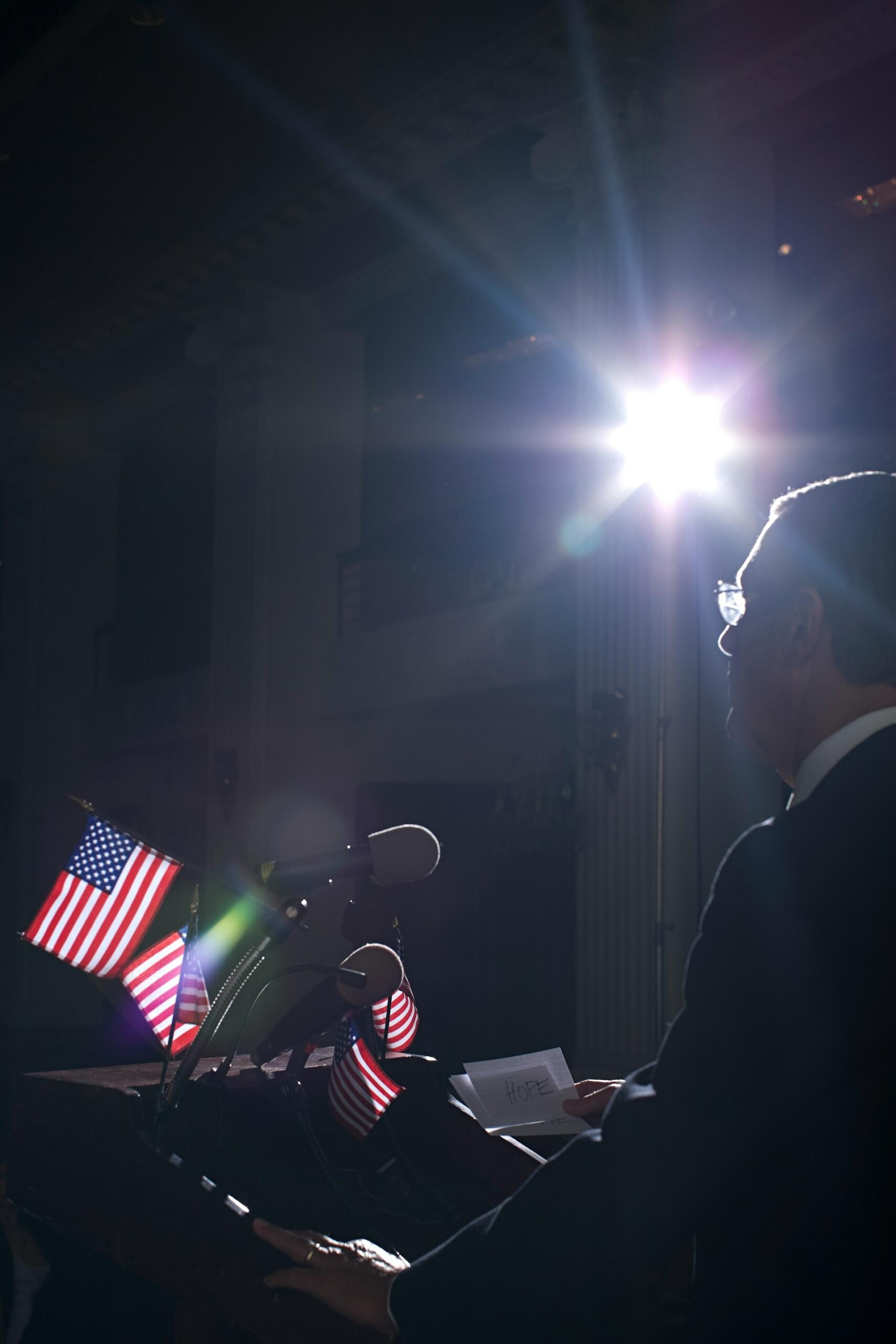 Politik reční pri pulte s americkými vlajkami