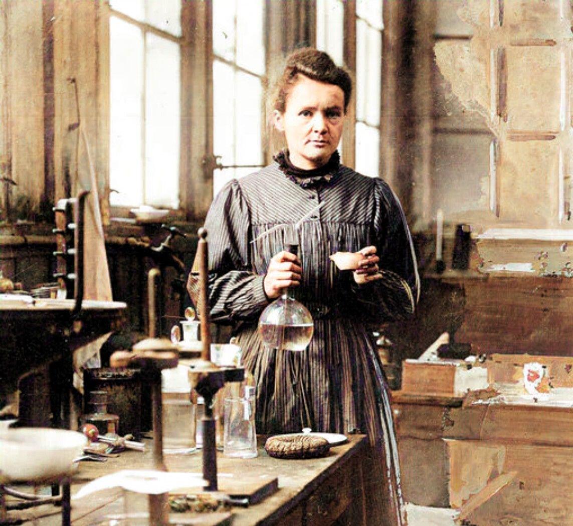 Marie Curie v laboratóriu drží sklenenú nádobu počas vedeckého výskumu