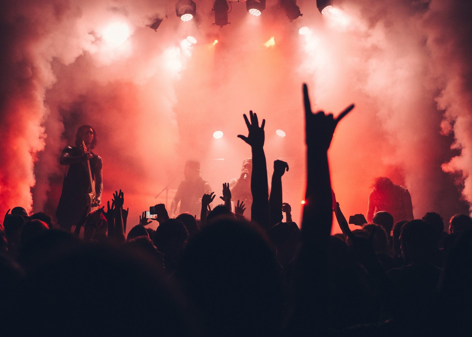 Rocková kapela počas koncertu pred davom fanúšikov