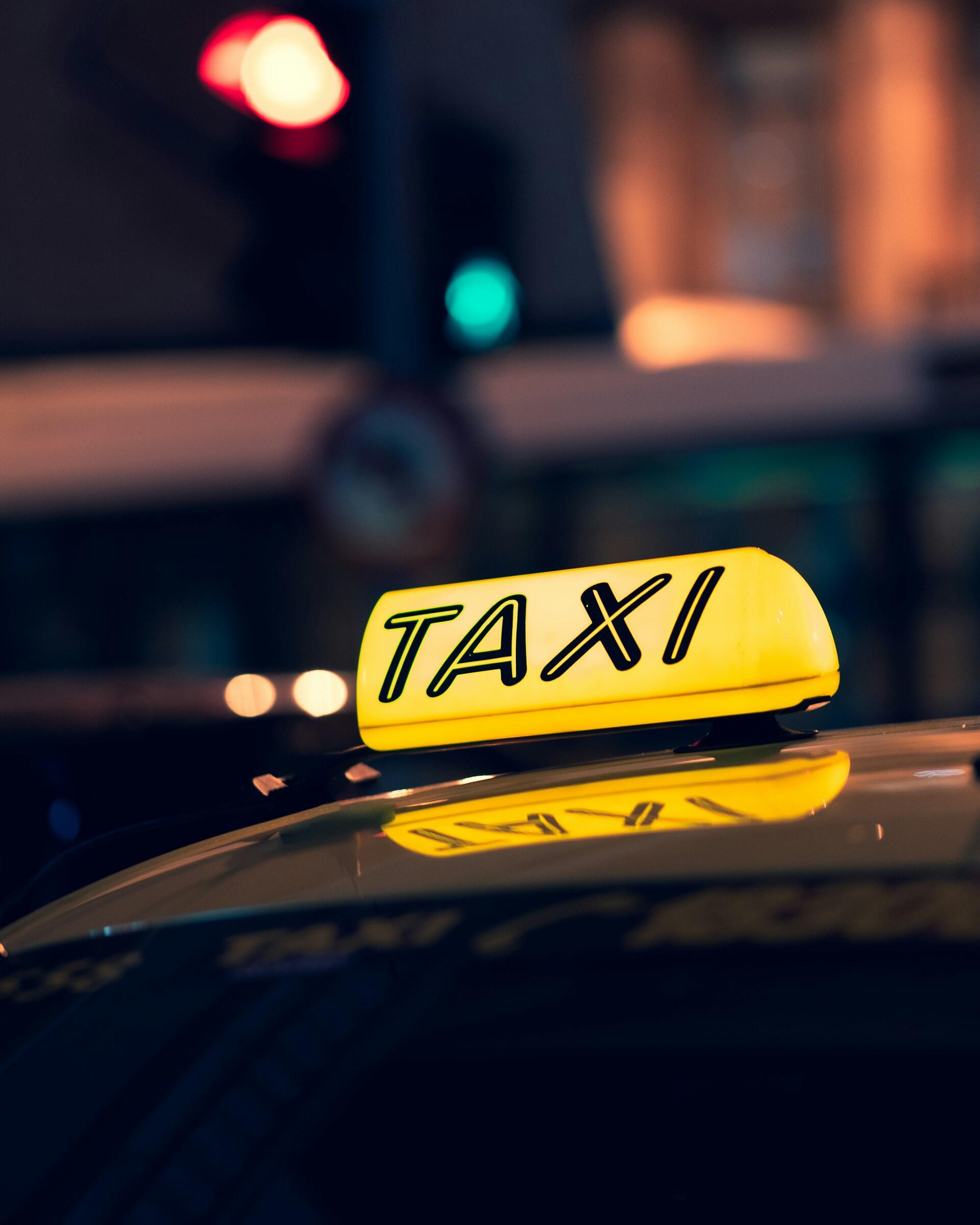 Svietiaci nápis TAXI na streche auta v nočnom meste
