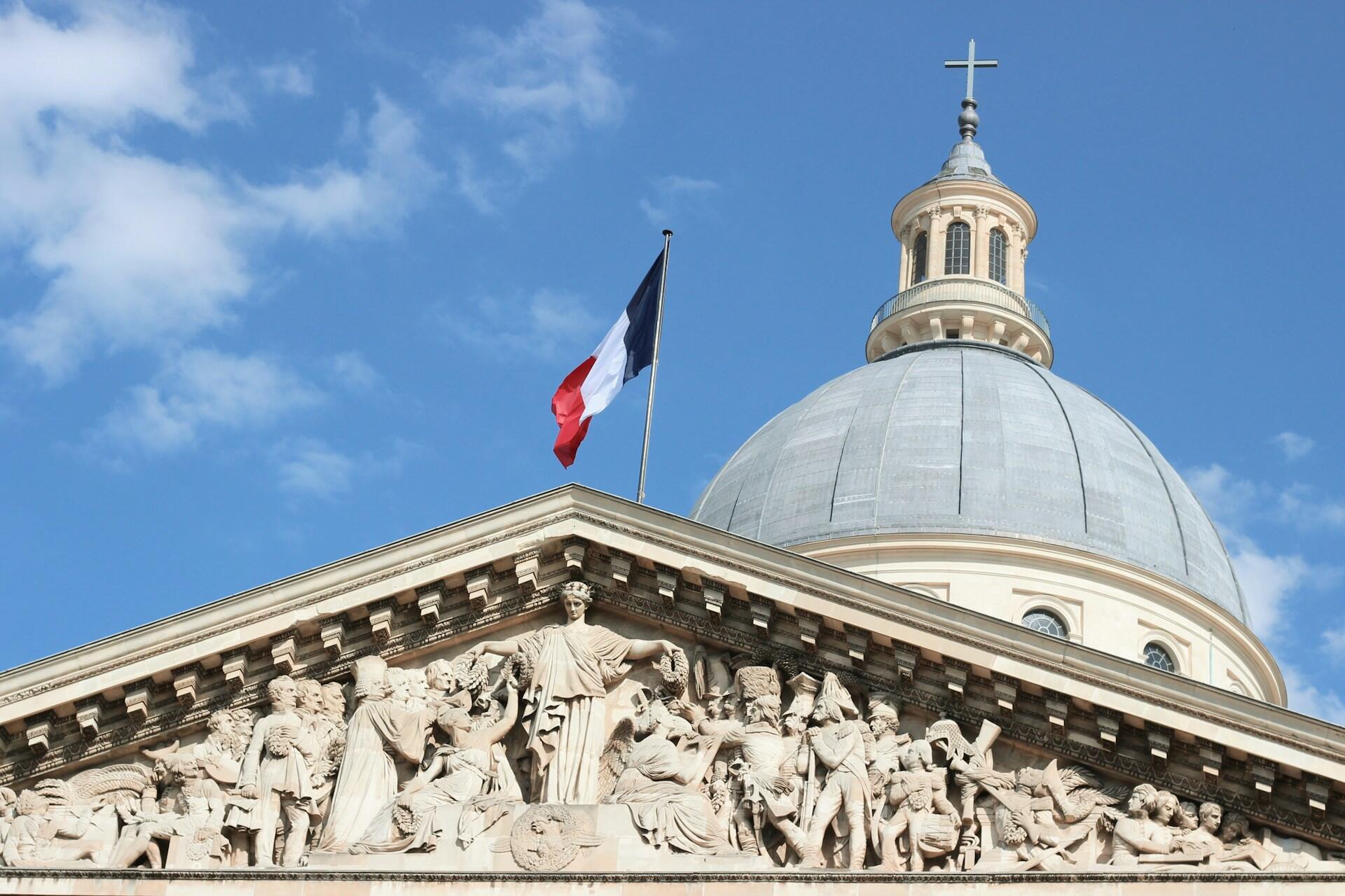 Historická budova s kupolou a francúzskou vlajkou symbolizujúca francúzsku históriu a štátnosť.