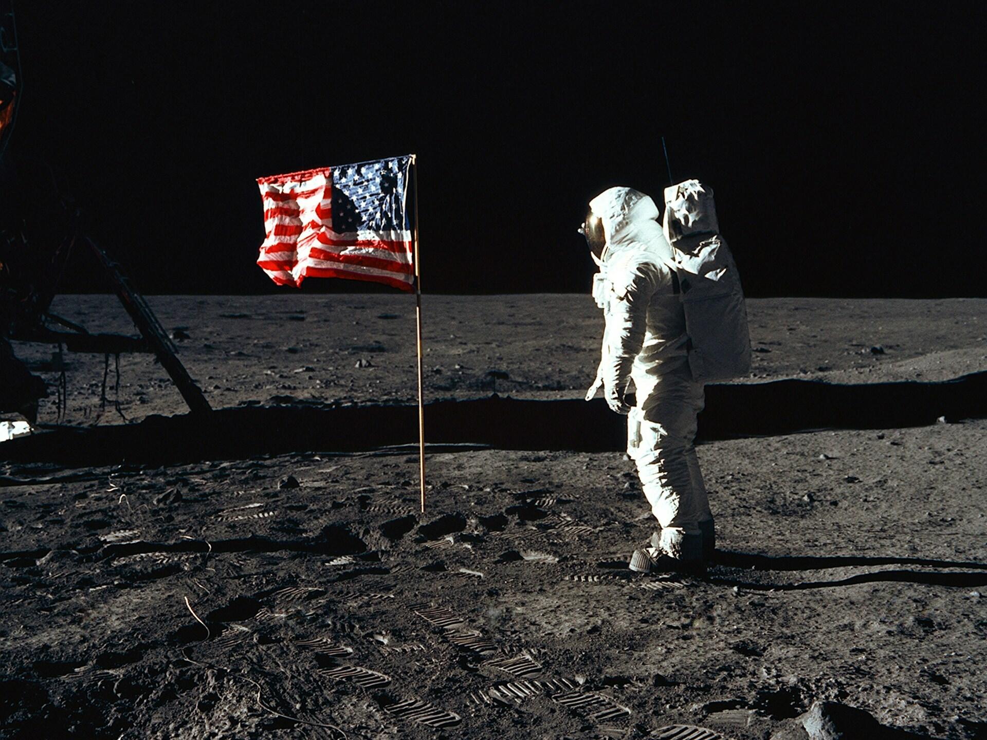 Astronaut na povrchu Mesiaca pri americkej vlajke.