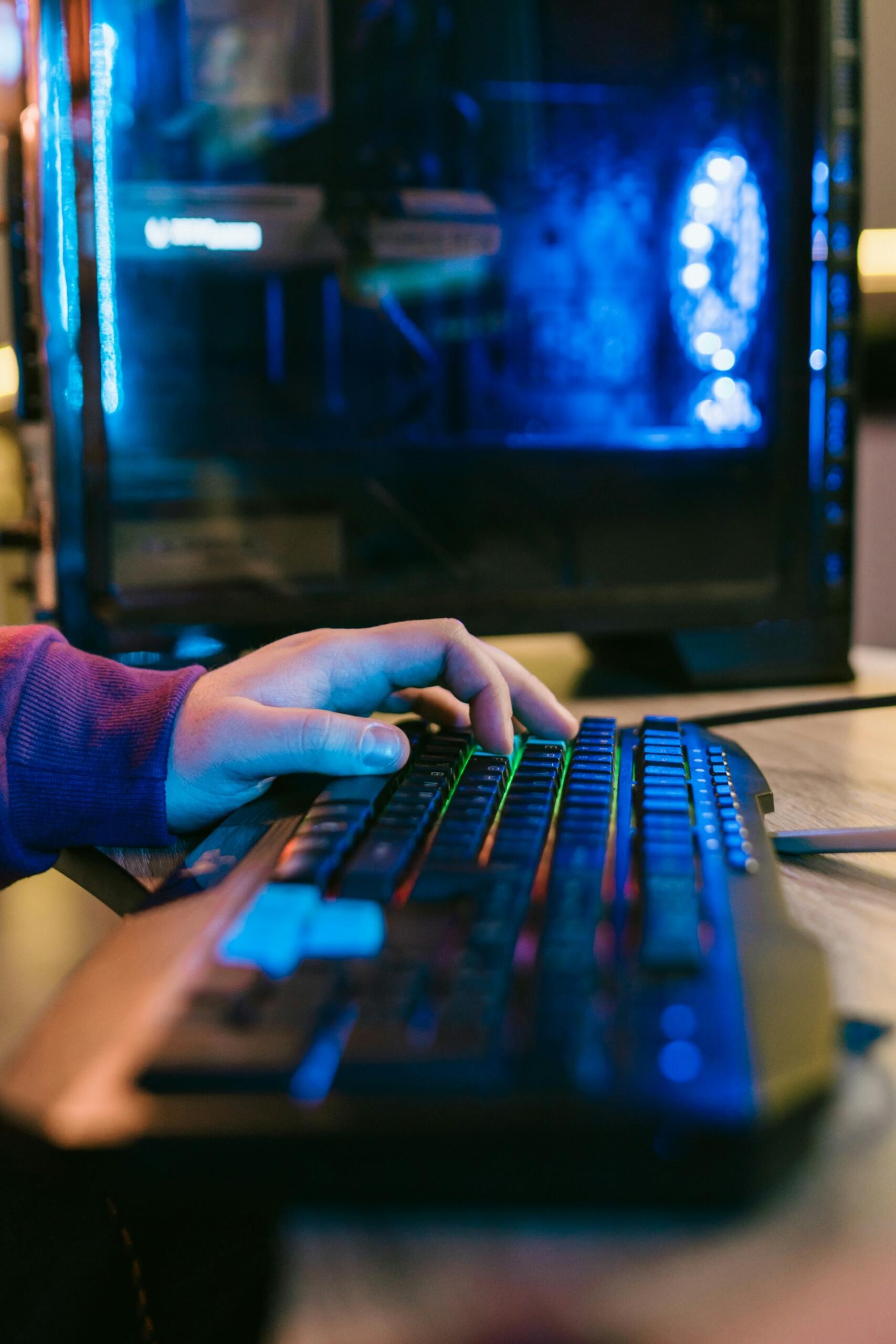 Hráč používa podsvietenú klávesnicu pri hraní počítačovej hry na hernom PC.