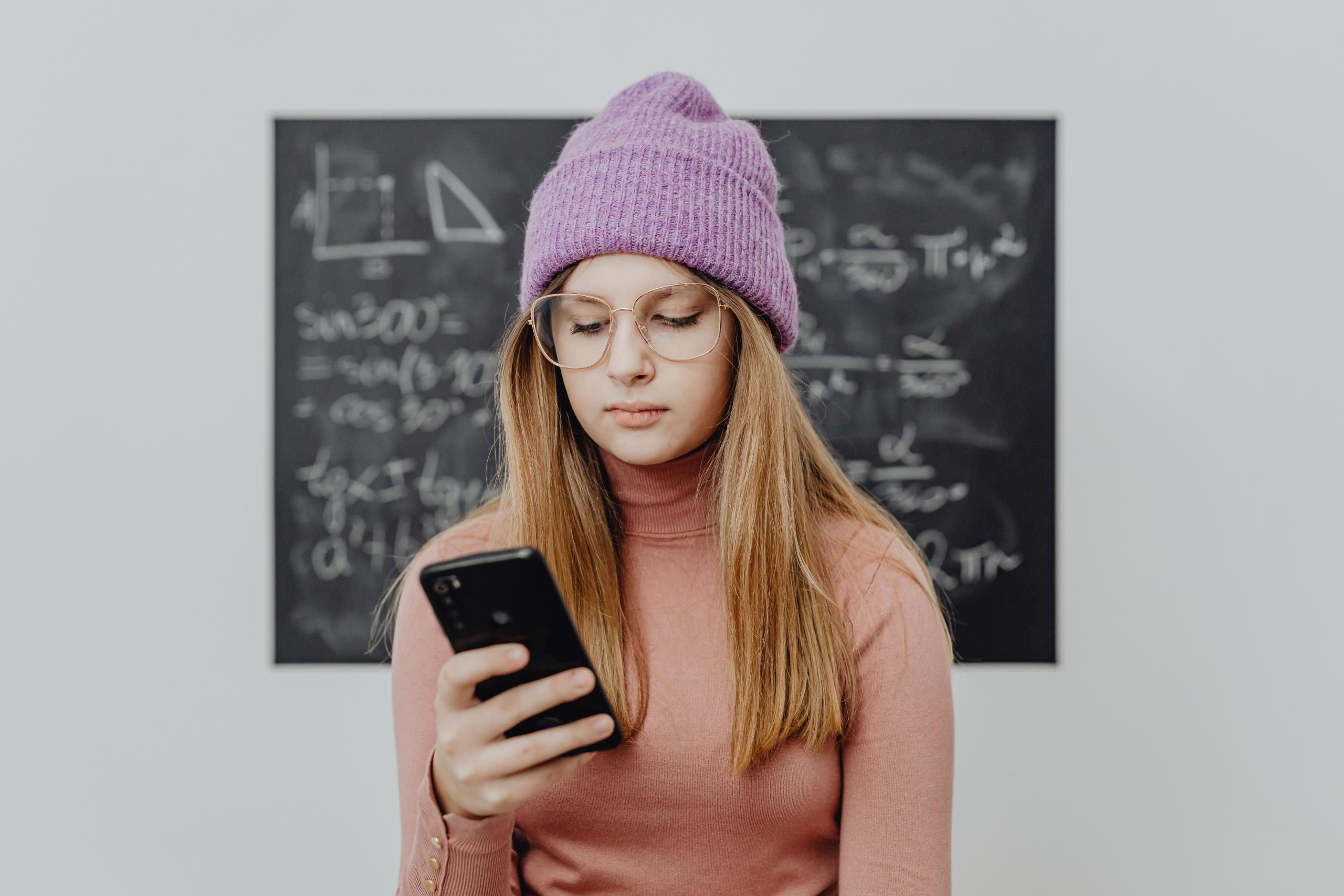 Mor bereli gözlüklü telefon tutan kız öğrenci