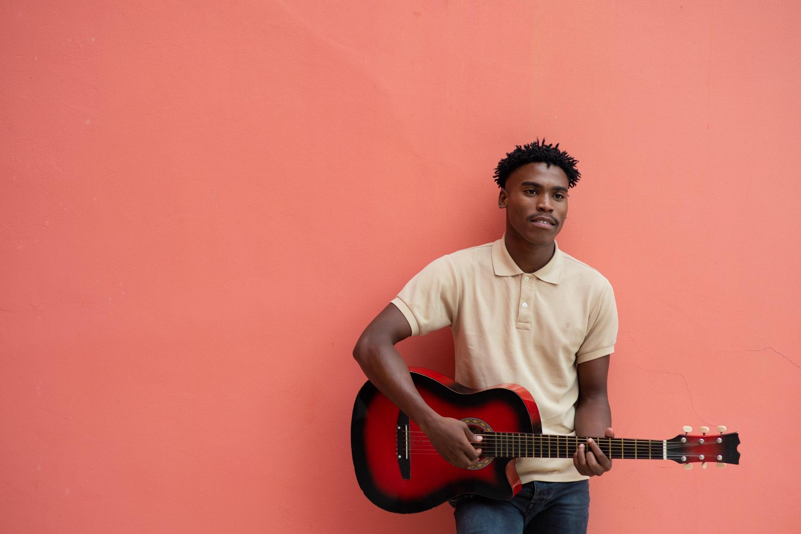 Pembe duvarın önünde gitar çalan adam