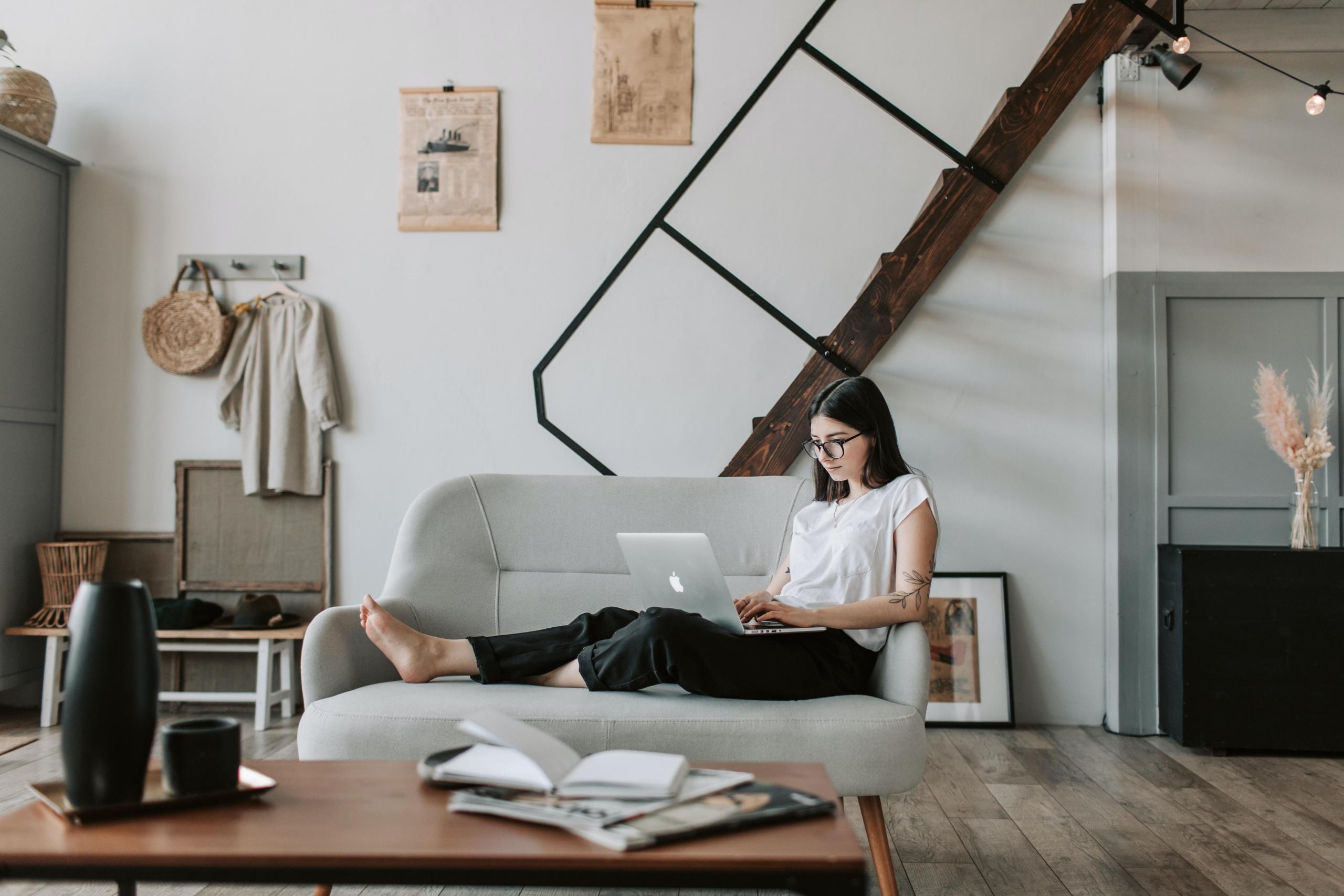 Apartman dairesinde kanepede laptopla oturan kadın