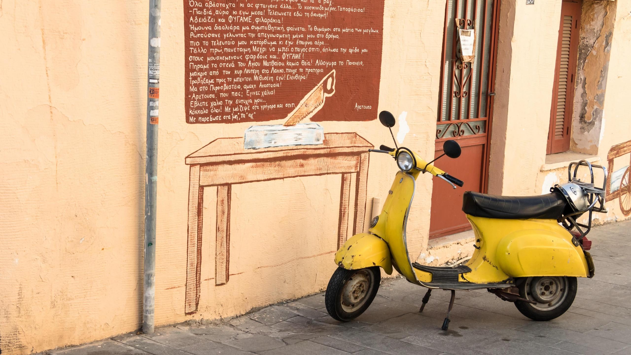 Resimli duvarın önünde sarı Vespa